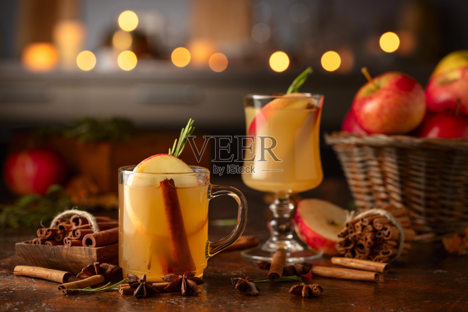 在燃烧的蜡烛背景下，加入苹果、肉桂、迷迭香和茴香的热苹果酒。照片摄影图片