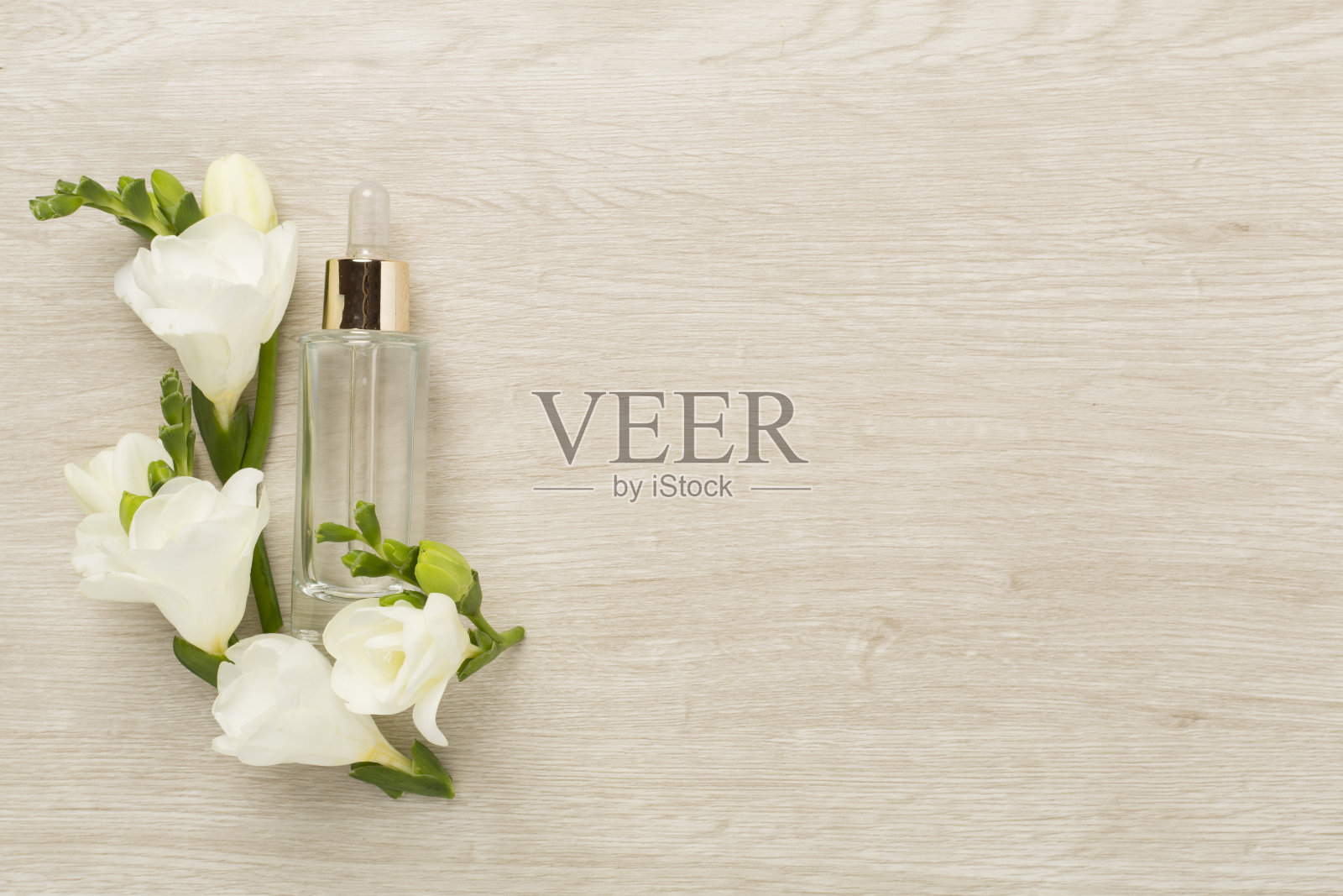 化妆品瓶与小苍兰花在木制背景，俯视图照片摄影图片