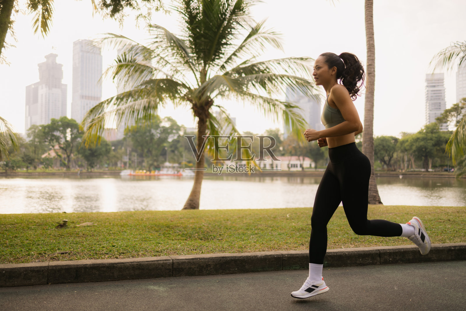 泰国女运动员在湖边的公园里慢跑。照片摄影图片