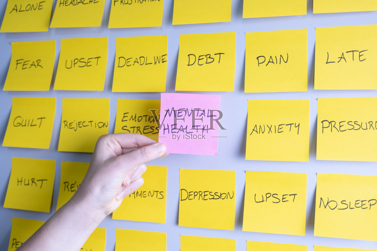 女人拿着贴在墙上的心理健康便利贴照片摄影图片