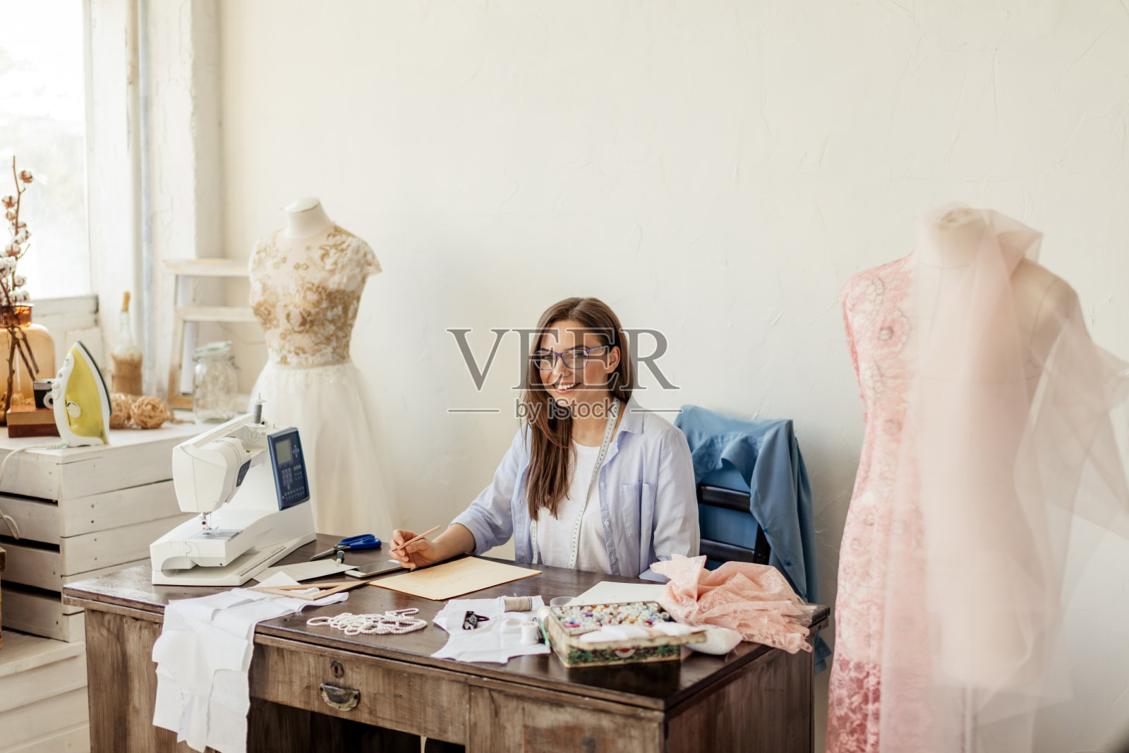 工作中的时装设计师。才华横溢的女裁缝在她的工作空间里画素描照片摄影图片