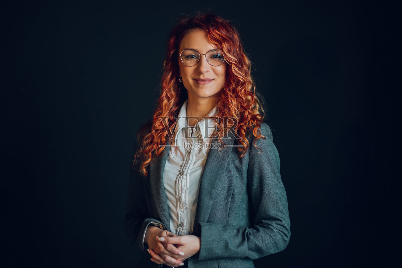 一个自信的女商人对着黑色背景的相机微笑。照片摄影图片