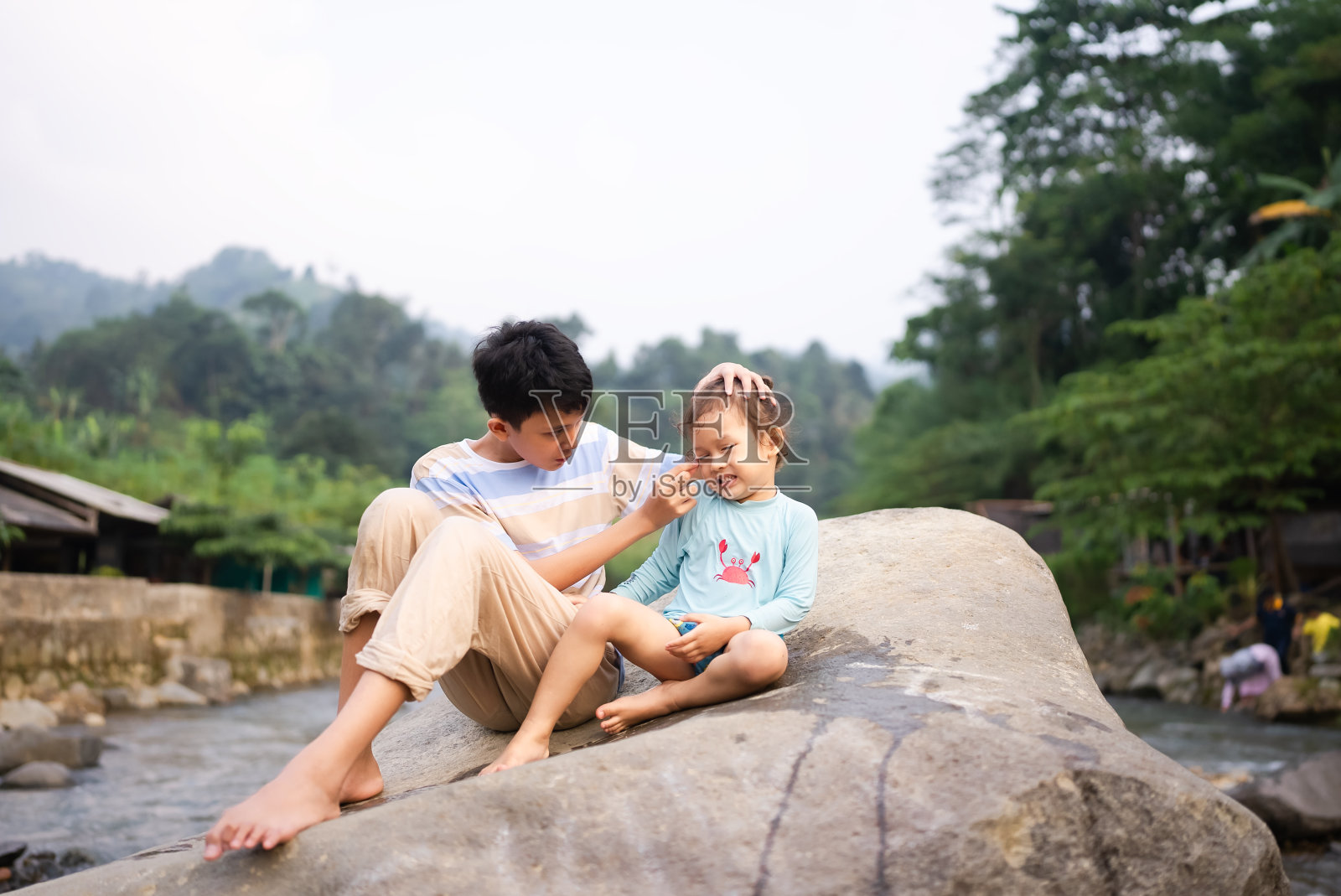 小男孩走在小溪里的石头上照片摄影图片