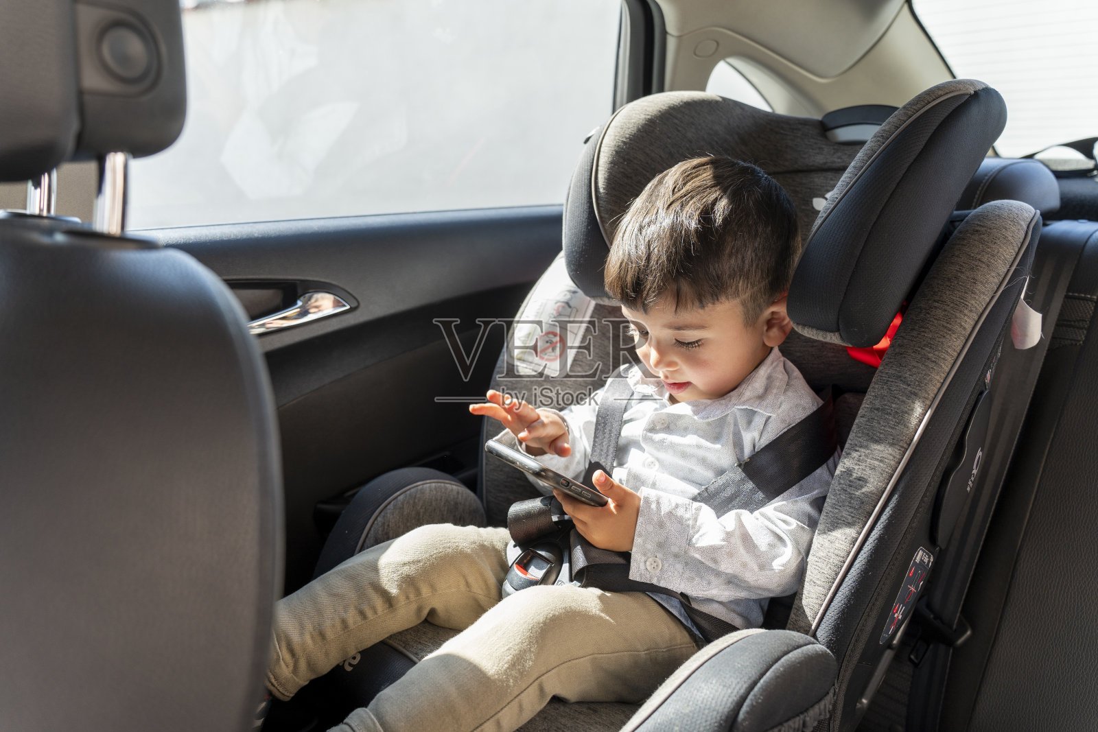 车里的婴儿座椅。可爱的男孩坐在汽车后座上。照片摄影图片