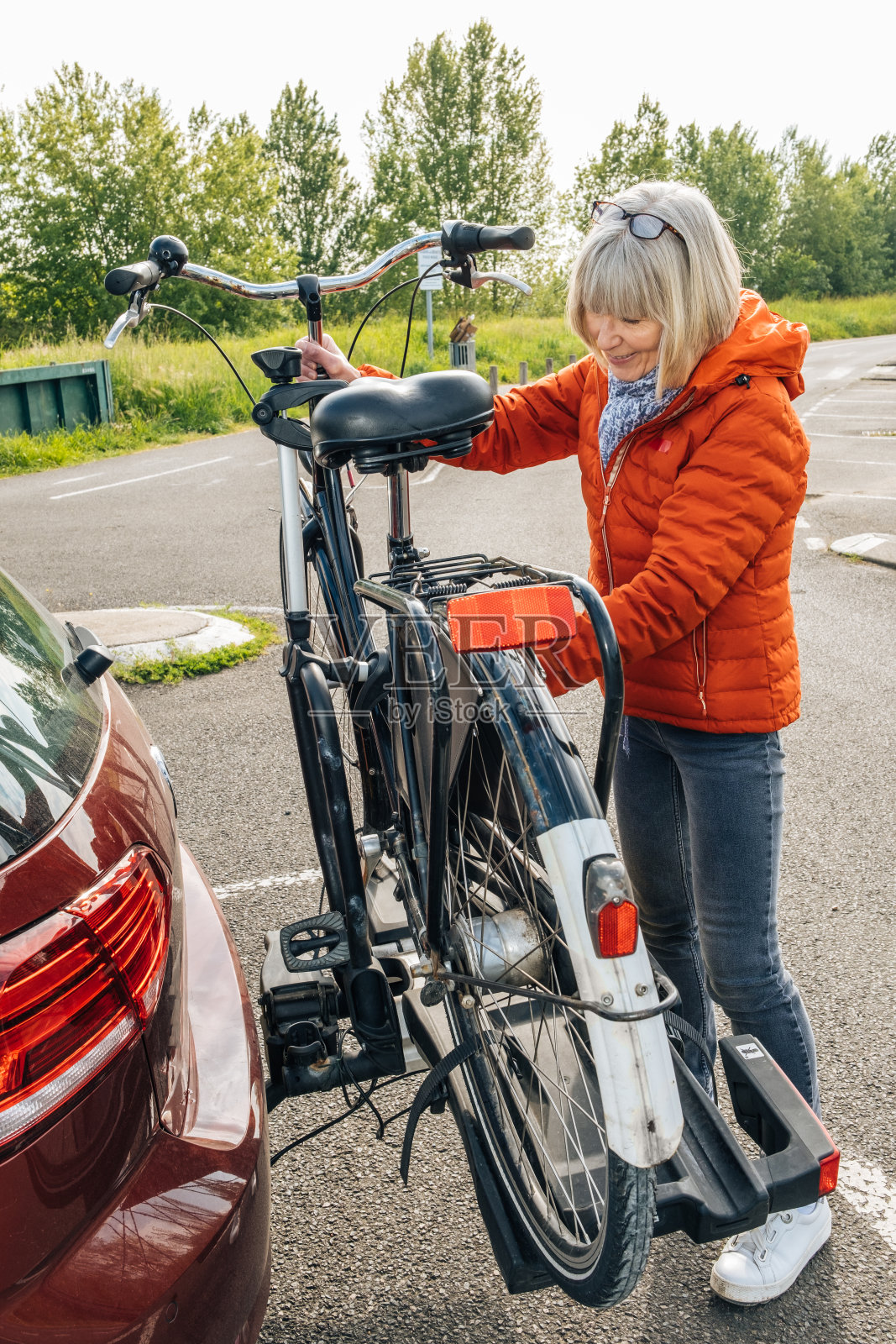 一位老年妇女正在从自行车架上卸下她的自行车照片摄影图片
