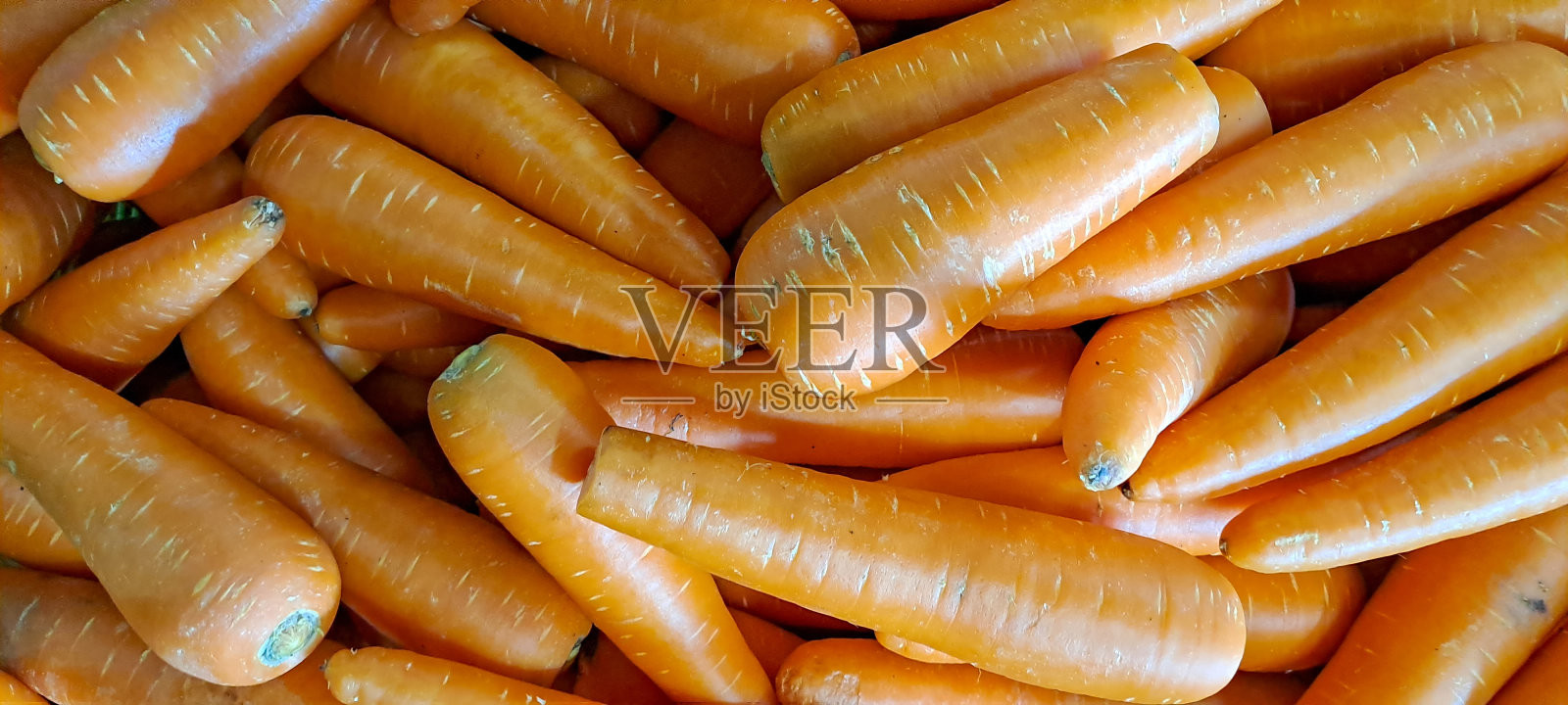 一堆新鲜的胡萝卜放在当地市场的柜台上照片摄影图片