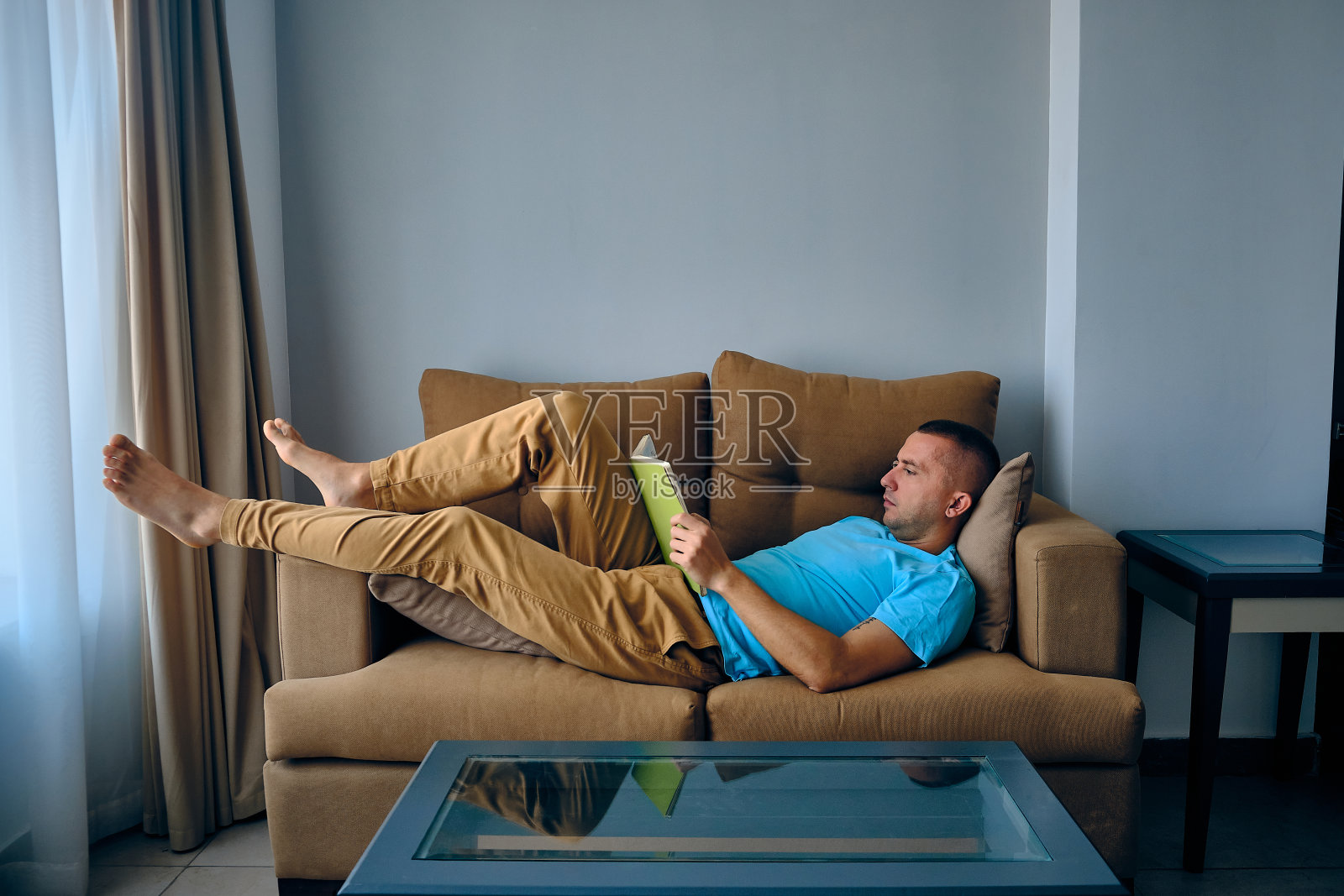 一个人躺在沙发上看书照片摄影图片