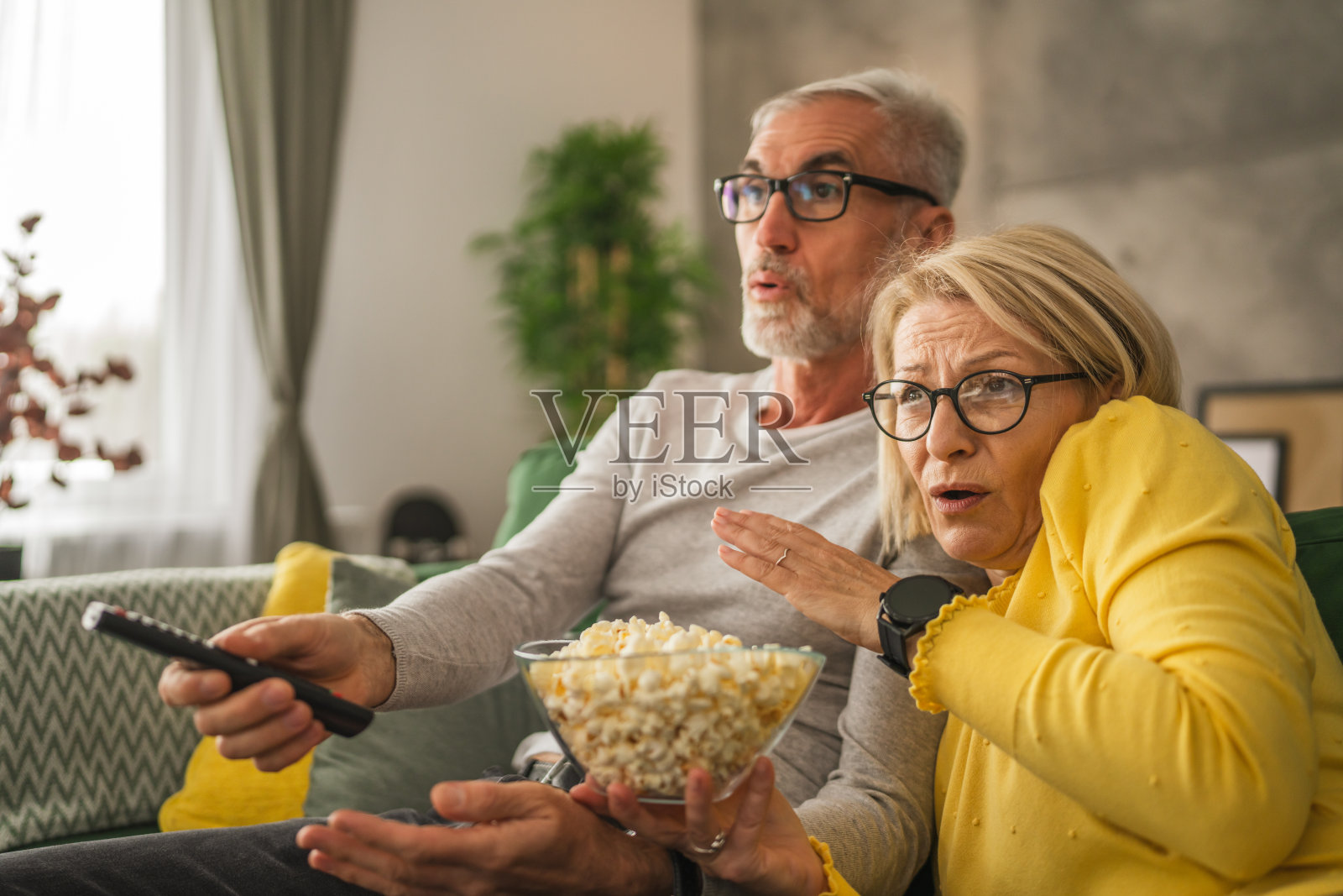 成熟的老夫妻一边看恐怖电影一边拿着爆米花照片摄影图片