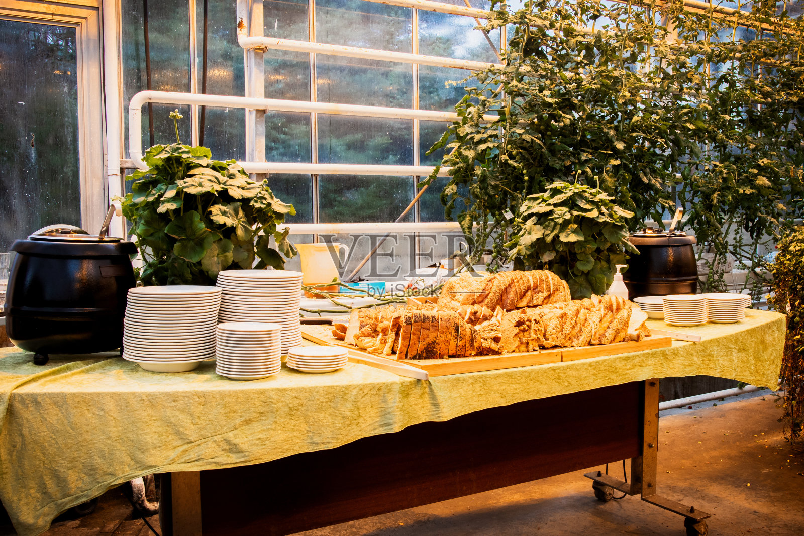 冰岛南部——2023年3月2日:在冰岛的Fridheimar——游客友好的番茄农场和餐馆，餐桌上的盘子和餐具上有汤和自制的面包照片摄影图片