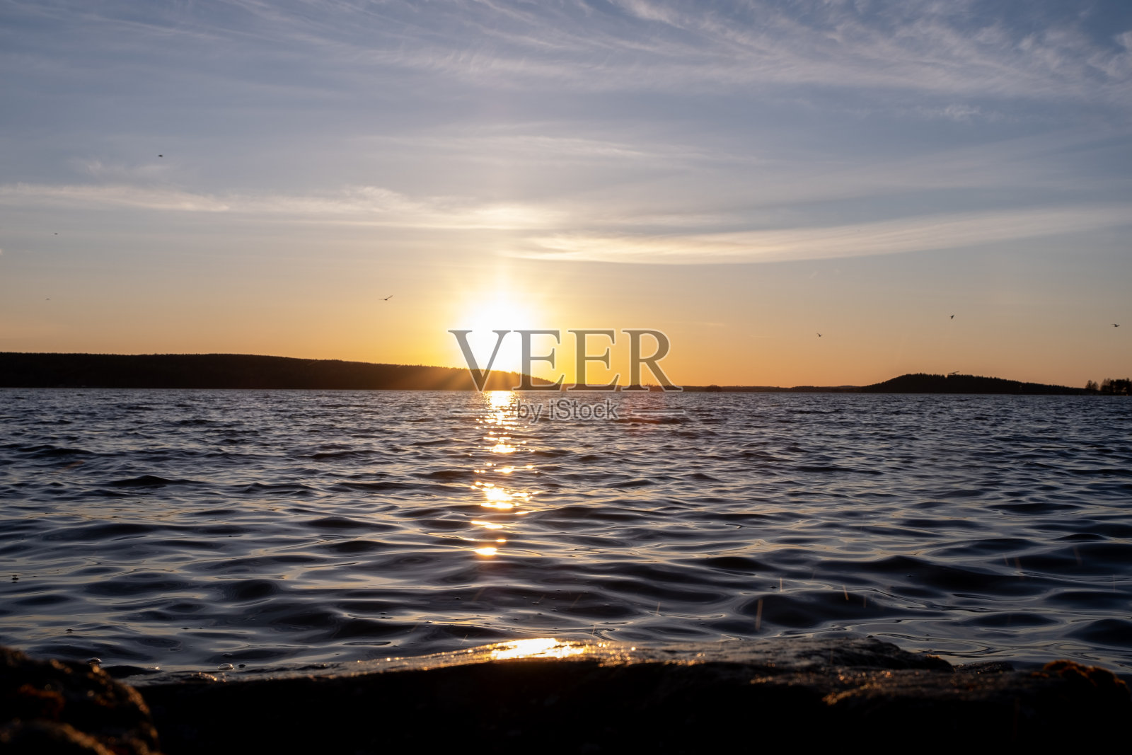 橘黄色的夕阳映在湖面上，水平线和水面上的阳光反射。照片摄影图片