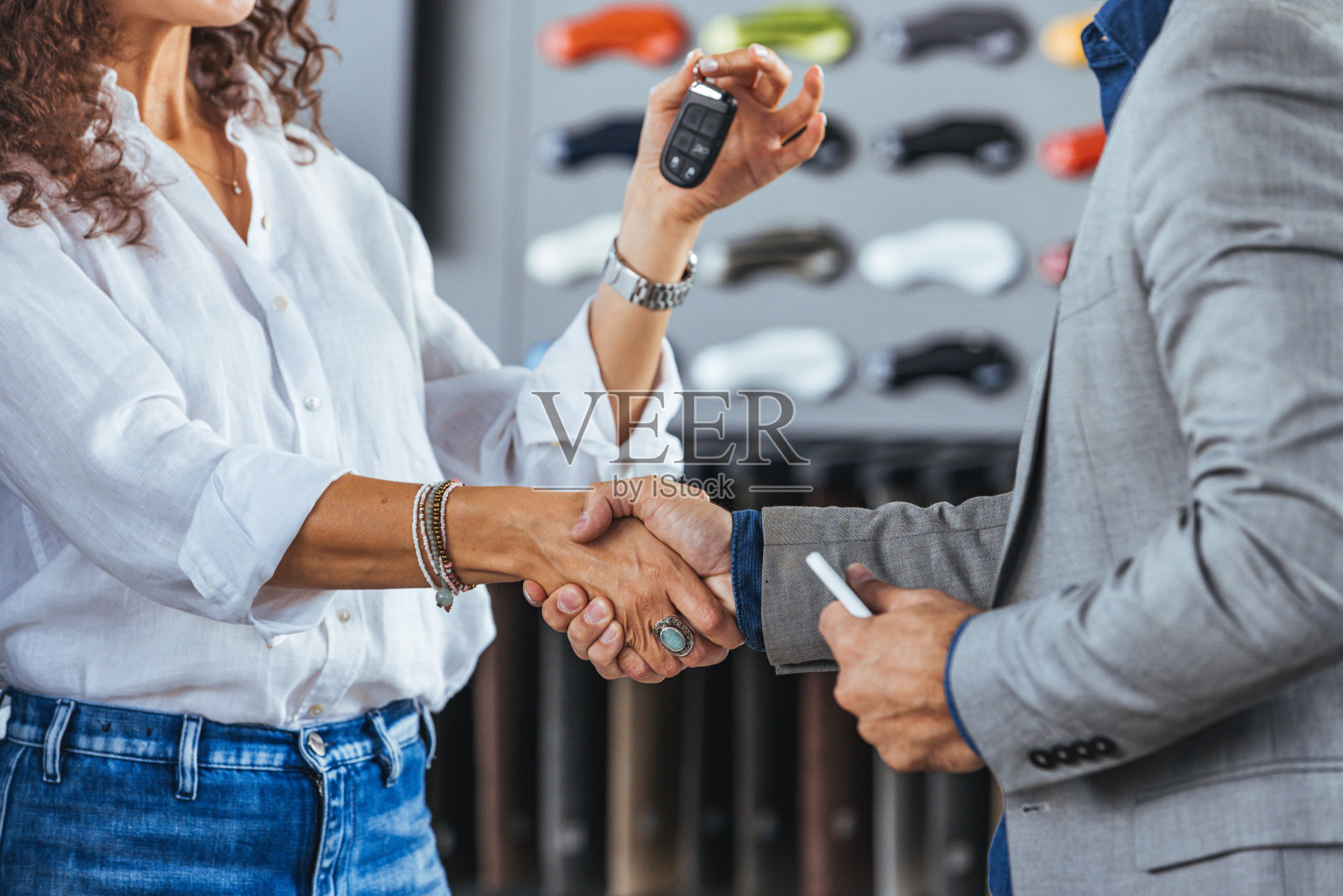 快乐的推销员祝贺他的女顾客在展示厅买了一辆新车。照片摄影图片