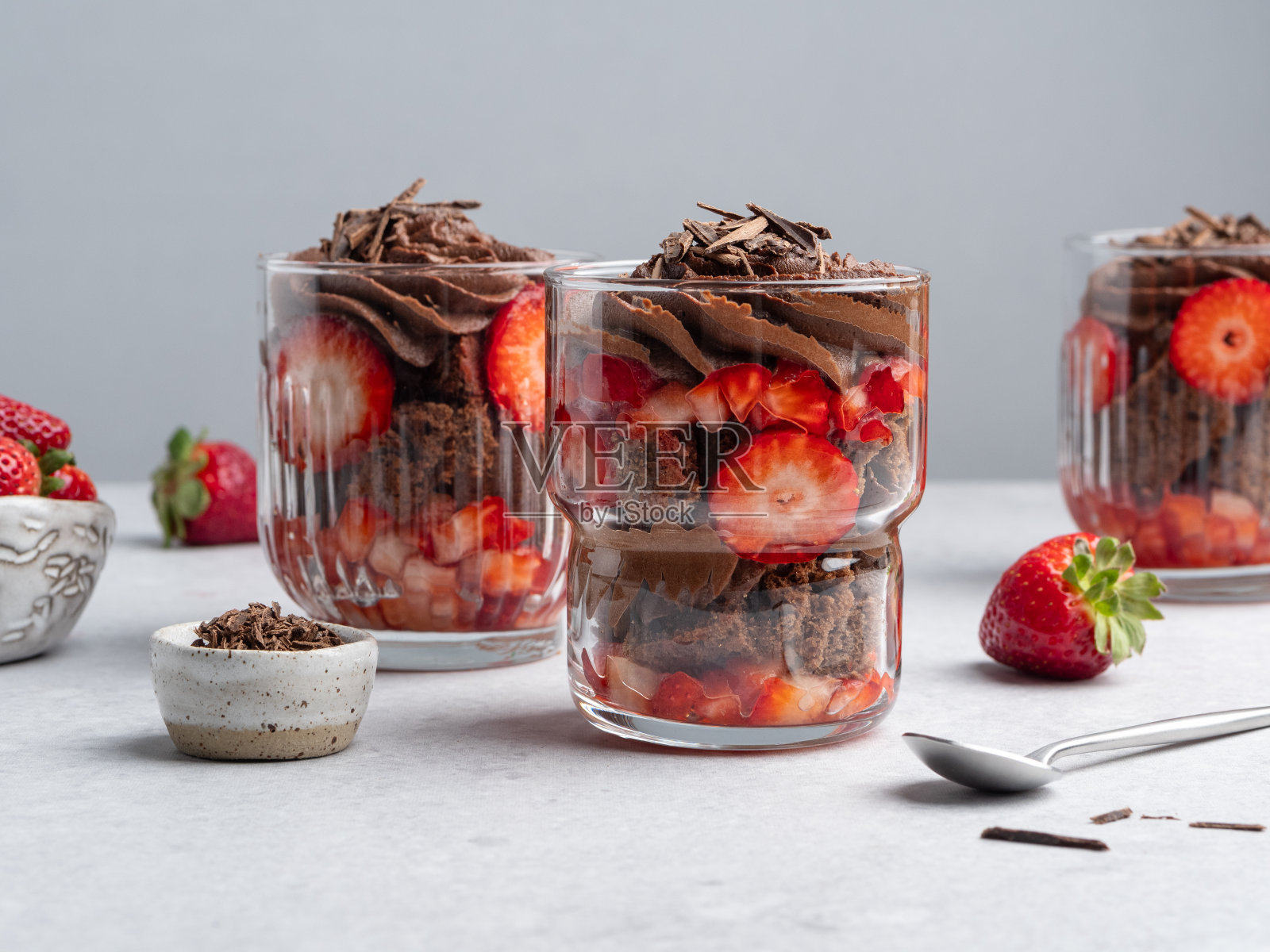 由巧克力海绵蛋糕、黑巧克力鲜奶油和新鲜红草莓制成的分层甜点。夏天的糖果。照片摄影图片