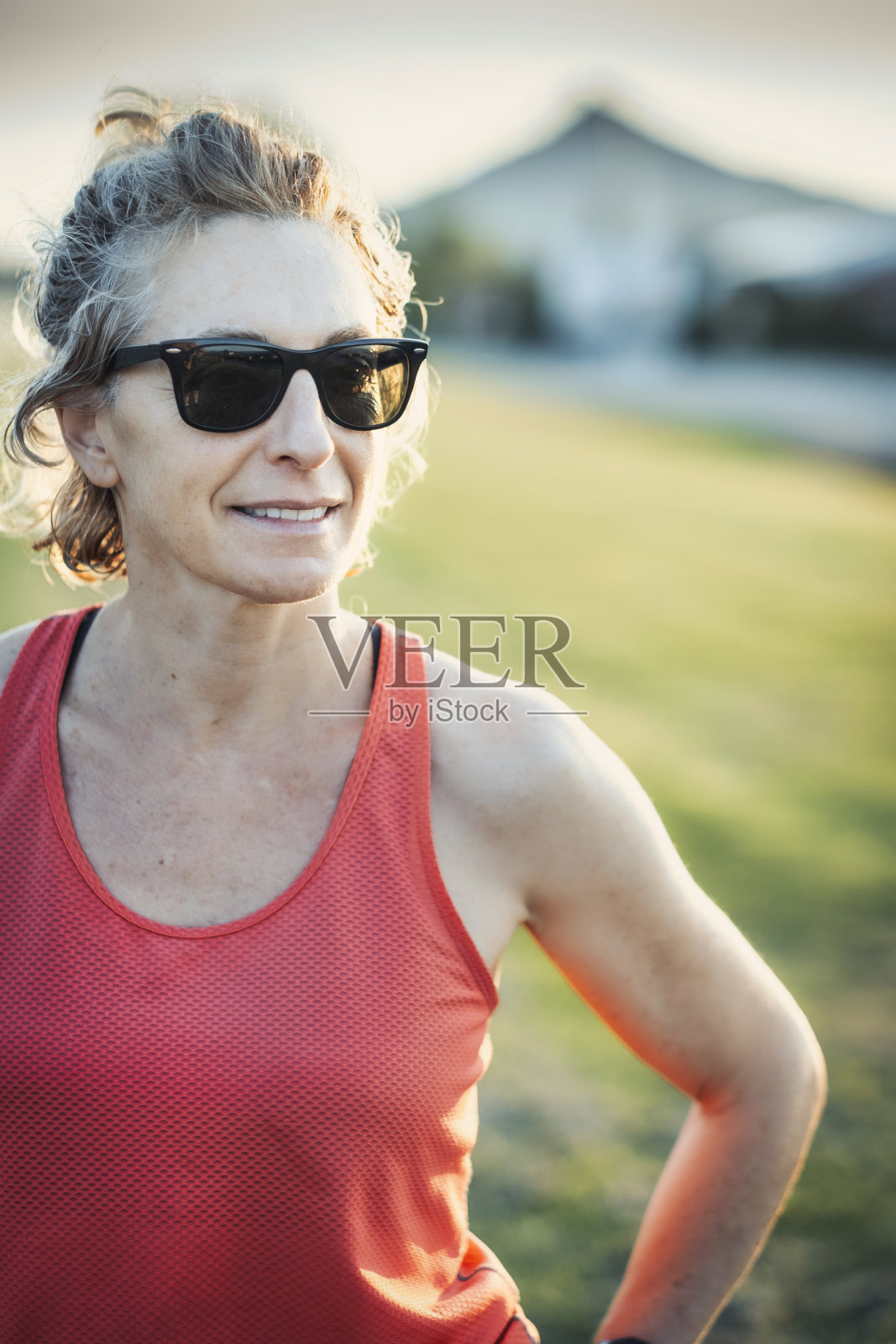 一位身穿橙色背心、戴着墨镜的女士在微笑照片摄影图片