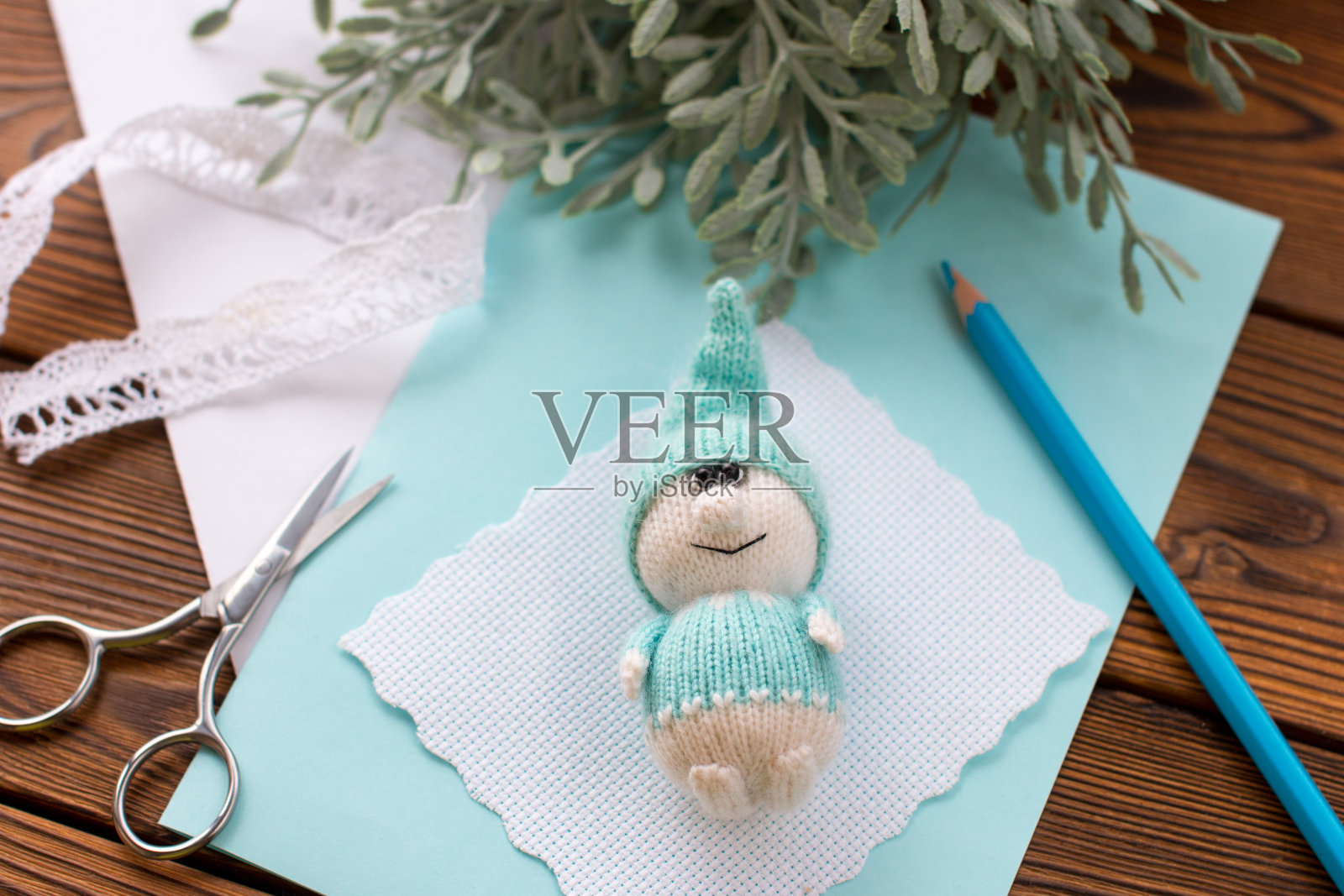 一个编织的蓝矮人拿着一支铅笔。手工制作，手工制作照片摄影图片