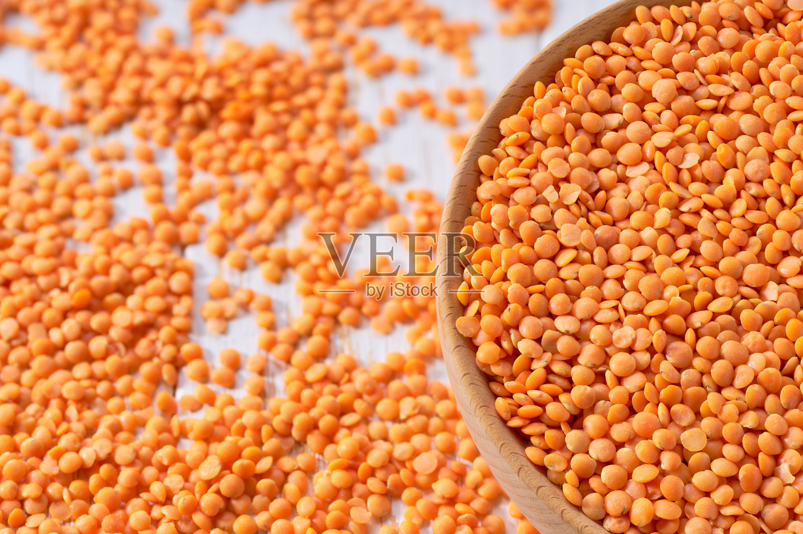 有机红扁豆散落在木碗里，在一张浅色的桌子上，选择性地聚焦。照片摄影图片