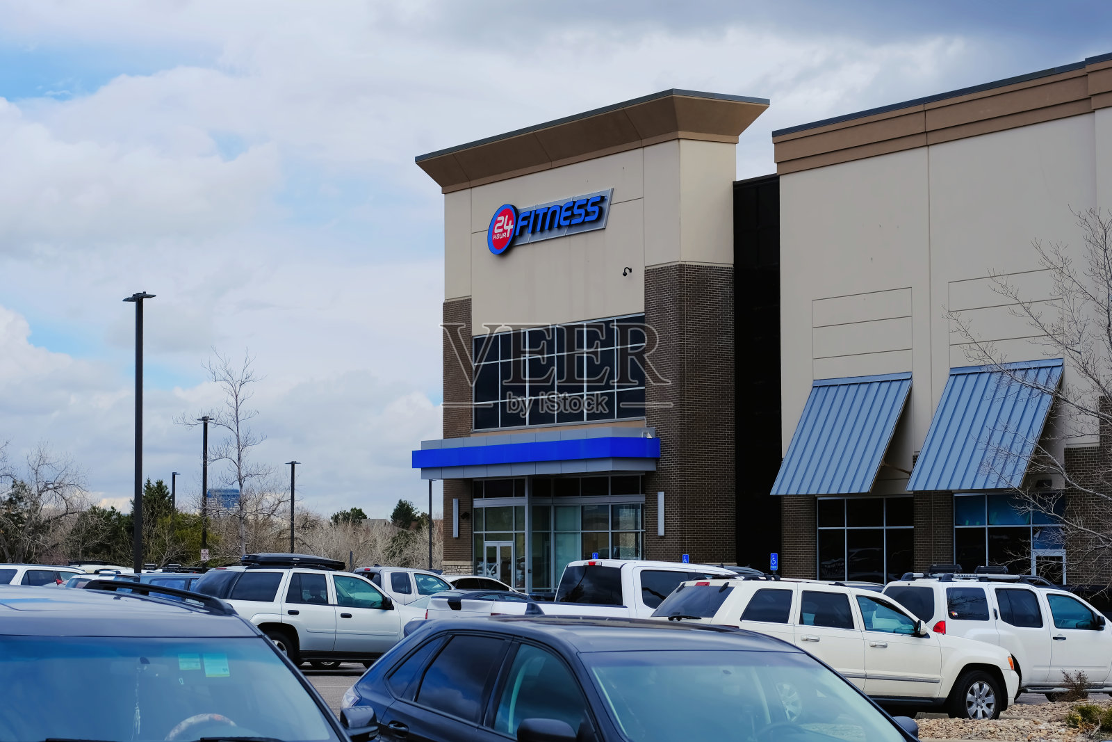 24小时健身运动中心大楼,有公司标志和停车场停放的汽车。热门健身馆体育俱乐部的位置。照片摄影图片