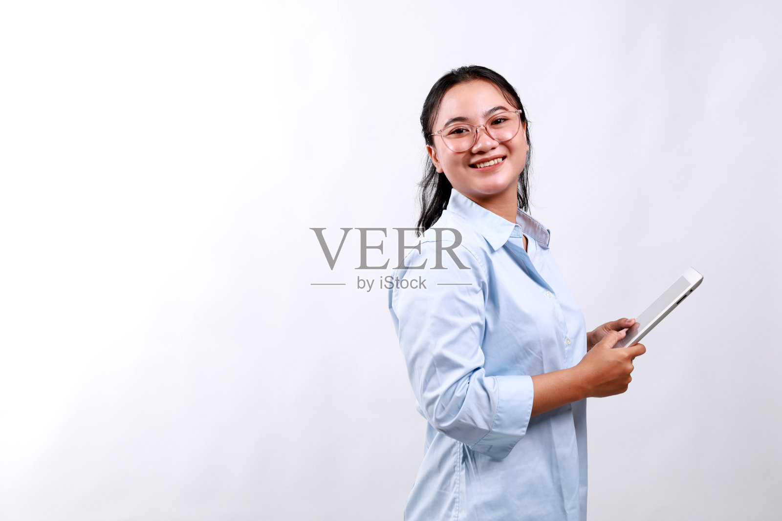 迷人的女商人手持数码平板电脑，站在白色背景上看着相机照片摄影图片