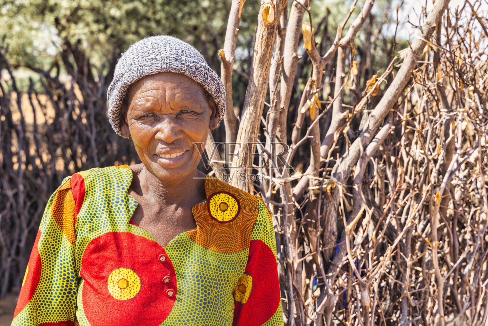 非洲村庄里，单身快乐的老奶奶满脸笑容地站在户外厨房前，院子里照片摄影图片