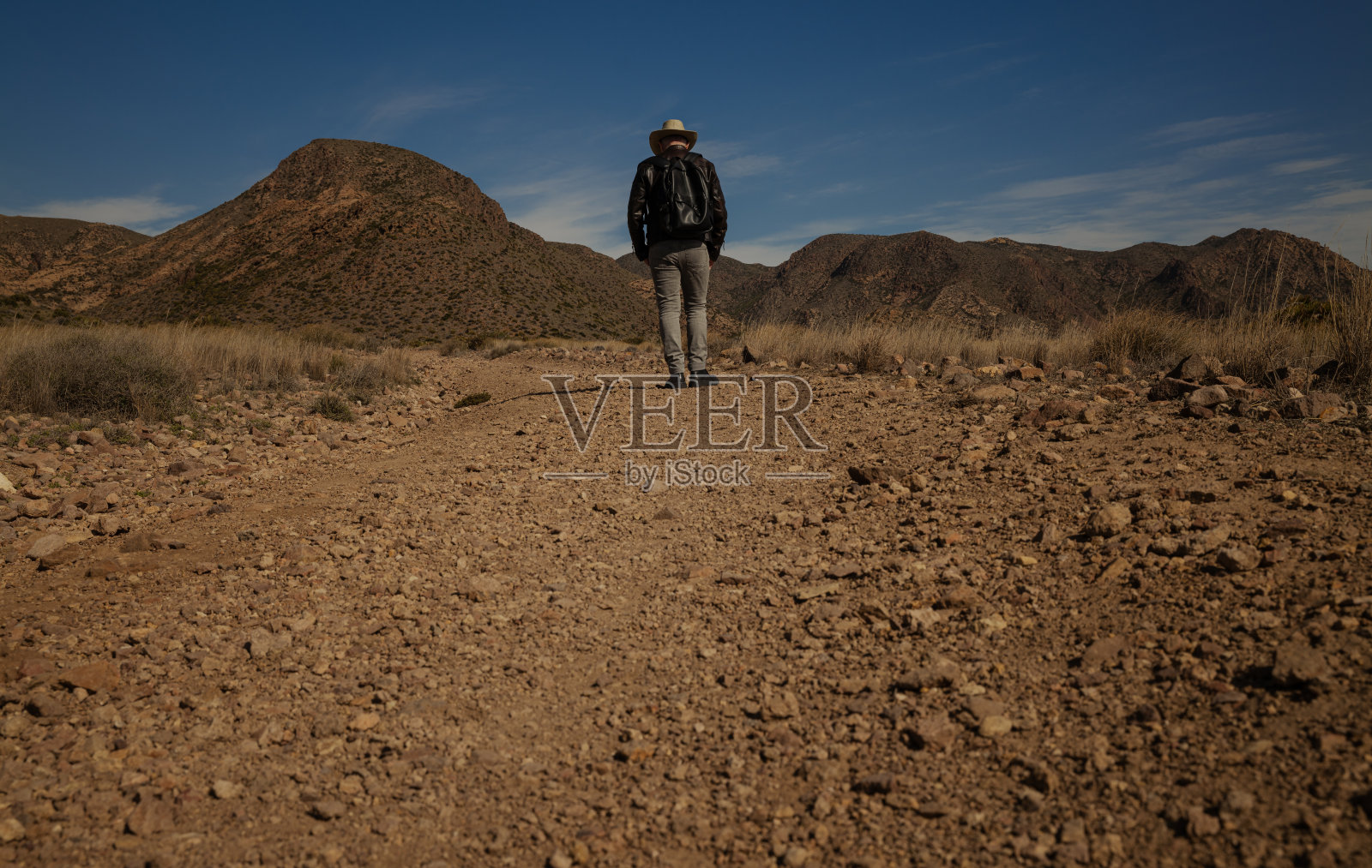 戴牛仔帽的成年男子在土路上的后视图照片摄影图片