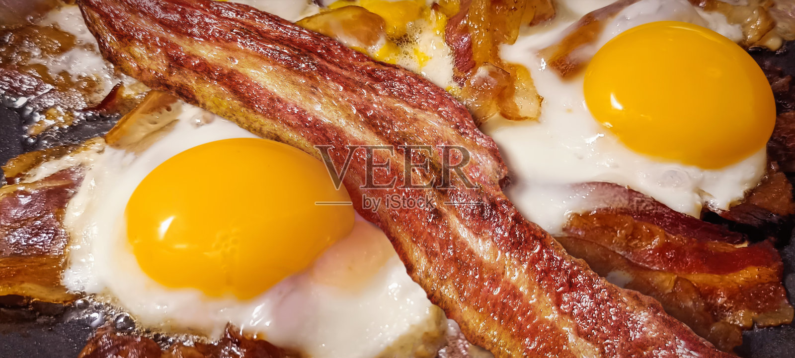 美味的美食脆培根片新鲜油炸诱人多汁的有机鸡蛋在黑色陶瓷涂层煎锅细节高分辨率库存图像照片摄影图片