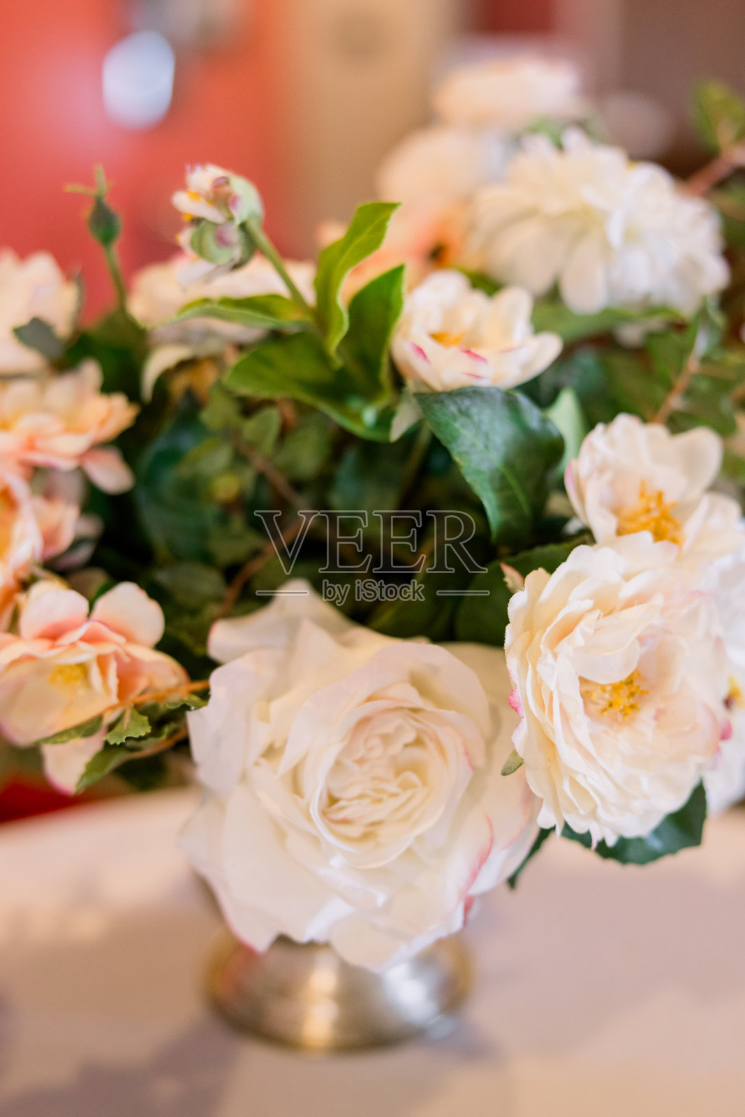 一张白色的桌子上放着一束美丽的玫瑰和绿色植物。照片摄影图片