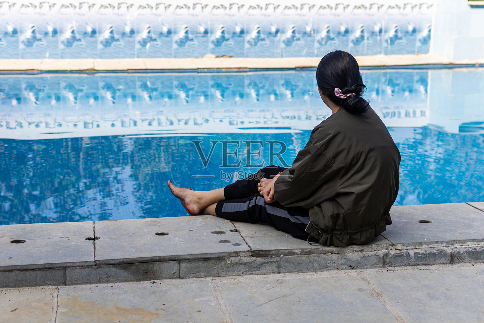 夏天早晨，一个孤独的印度女孩坐在游泳池附近照片摄影图片