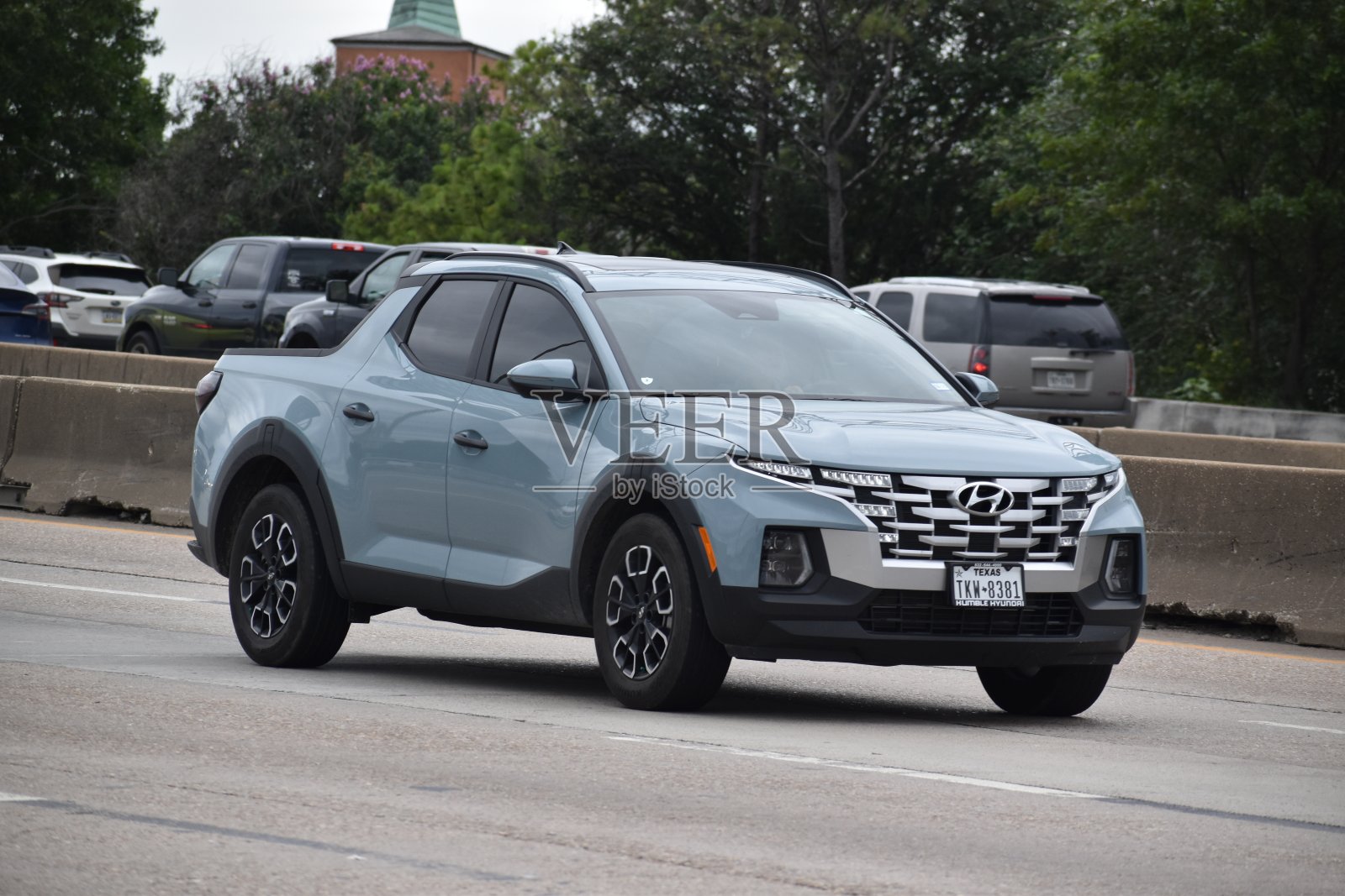 一辆蓝色的现代圣克鲁斯(一种独一无二的运动冒险车)行驶在交通温和的高速公路上的肖像照片摄影图片