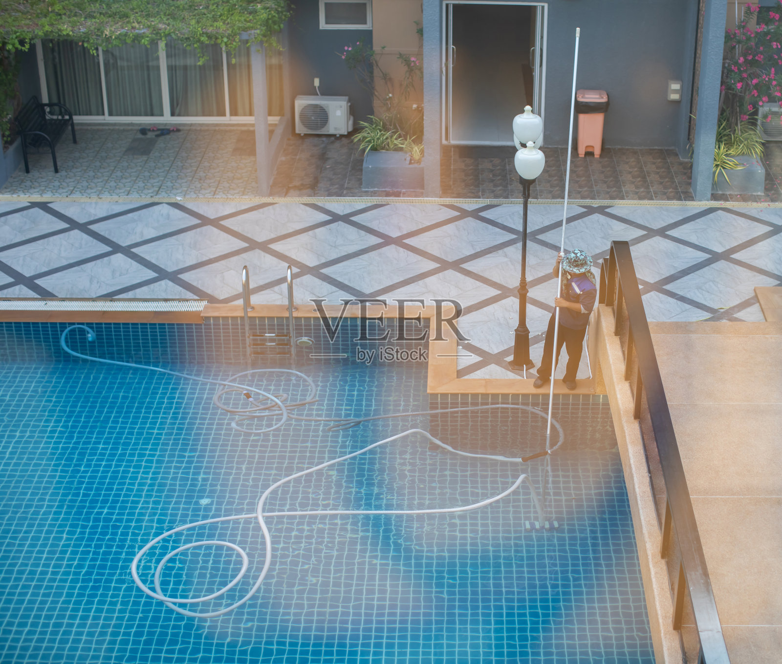 工作人员正在用水下真空泵清洁酒店游泳池。照片摄影图片