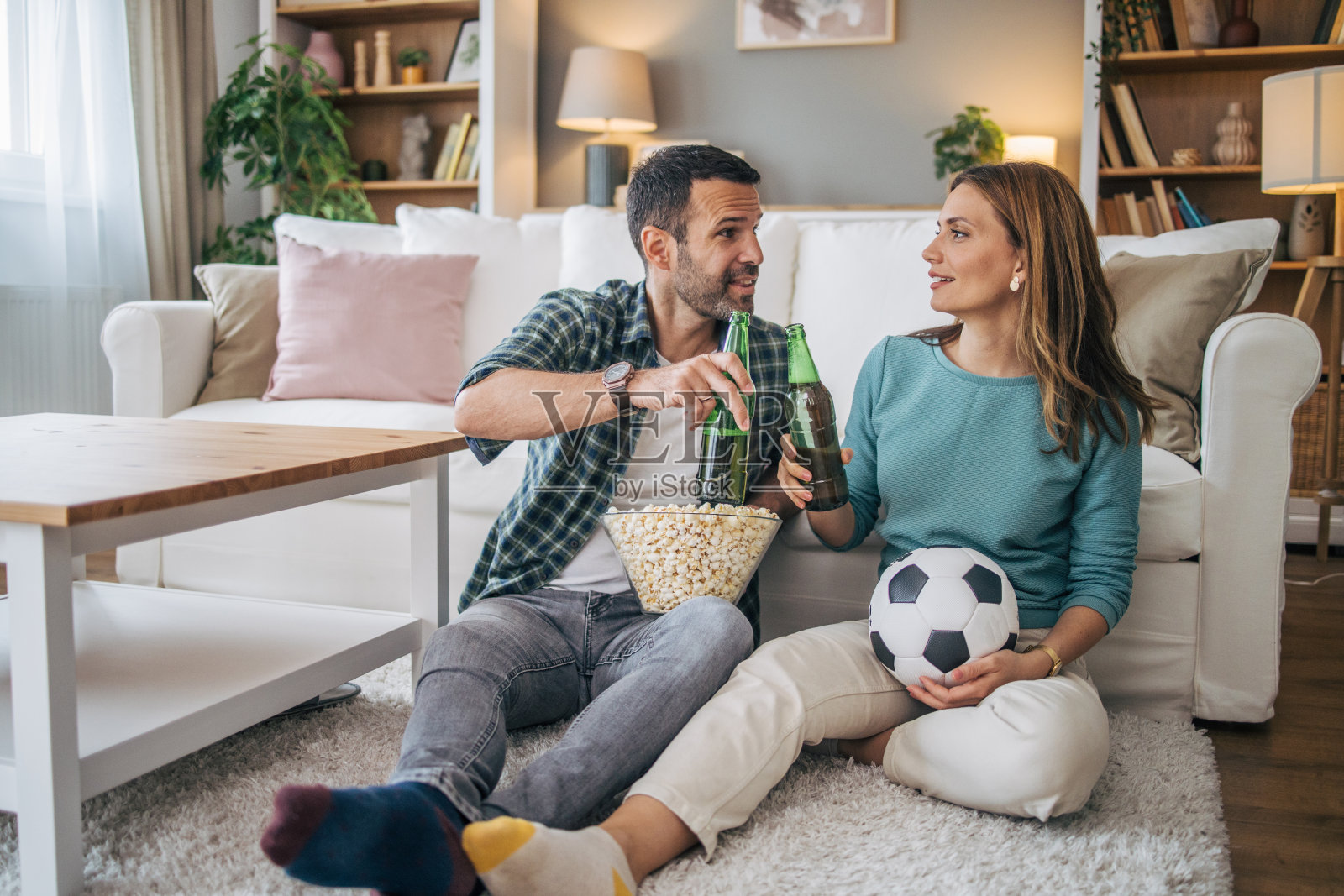 一对夫妇一边看足球比赛一边喝啤酒照片摄影图片