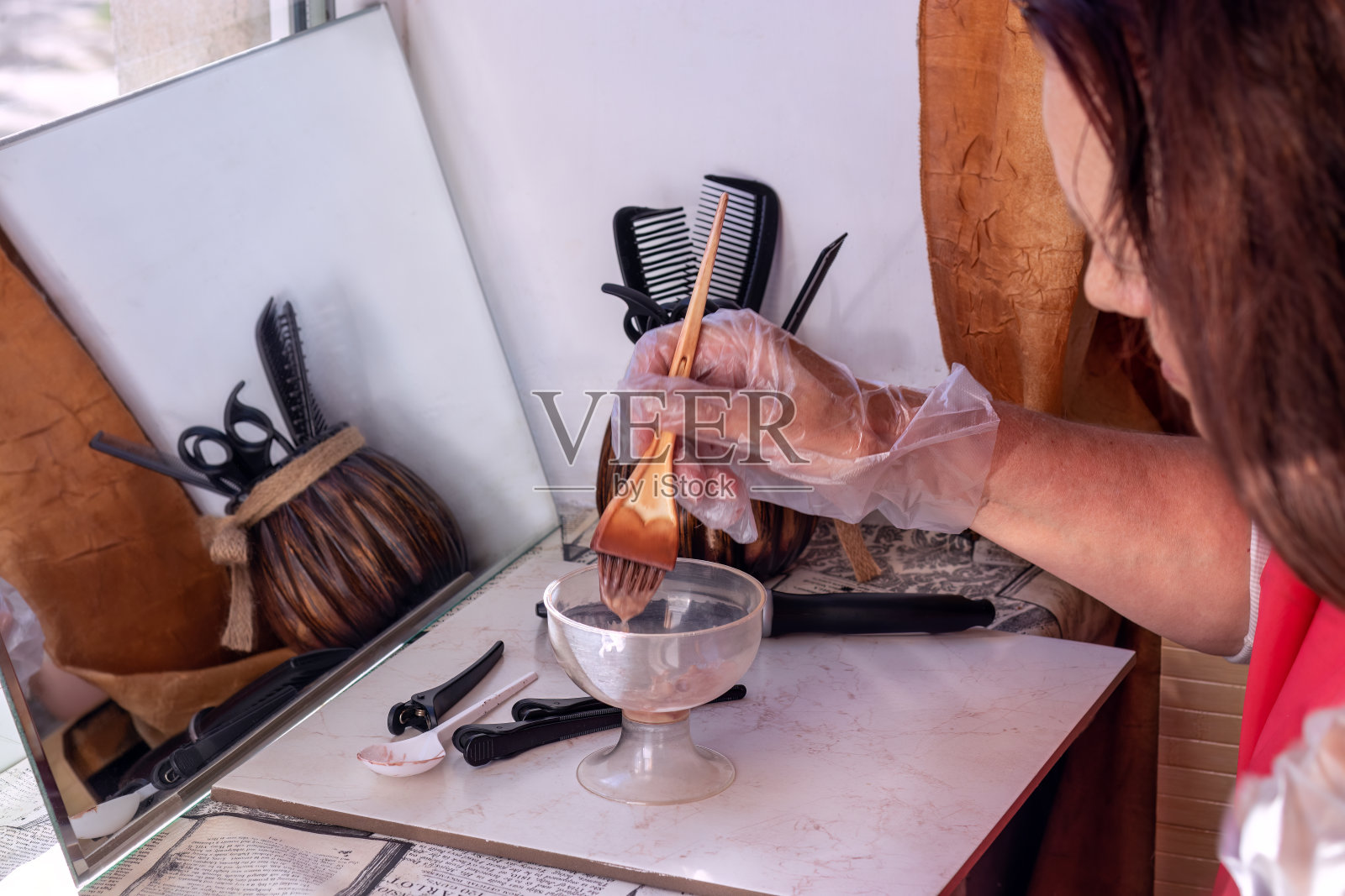 棕色头发的长头发女人在家里染发。一个女人用冰淇淋碗稀释颜料。照片摄影图片