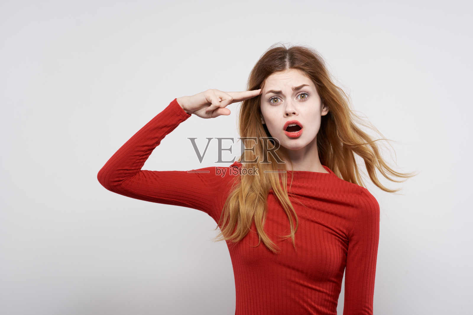 美丽的女人穿着红色的衣服摆出奢华的手势，浅色背景照片摄影图片