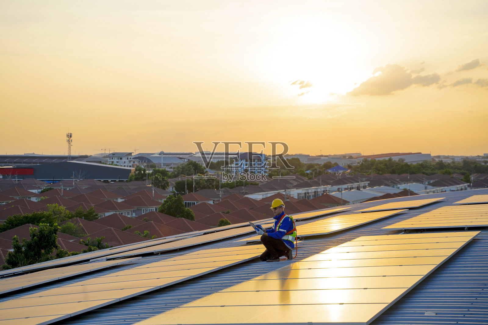 蓝领工人正在屋顶的太阳能电池板上工作。照片摄影图片