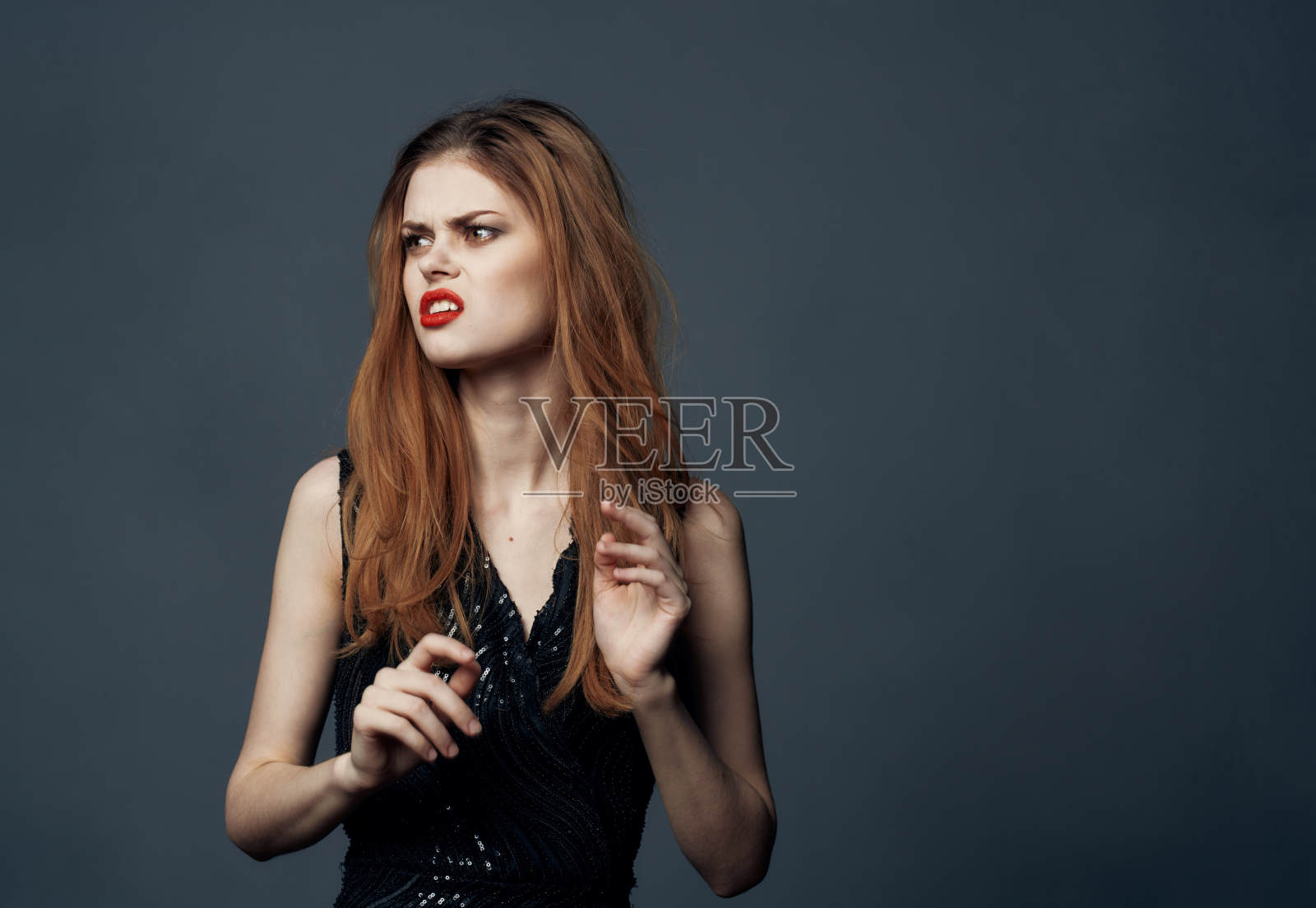 红发女士，身穿黑裙，红唇，用手示意，正面照片摄影图片