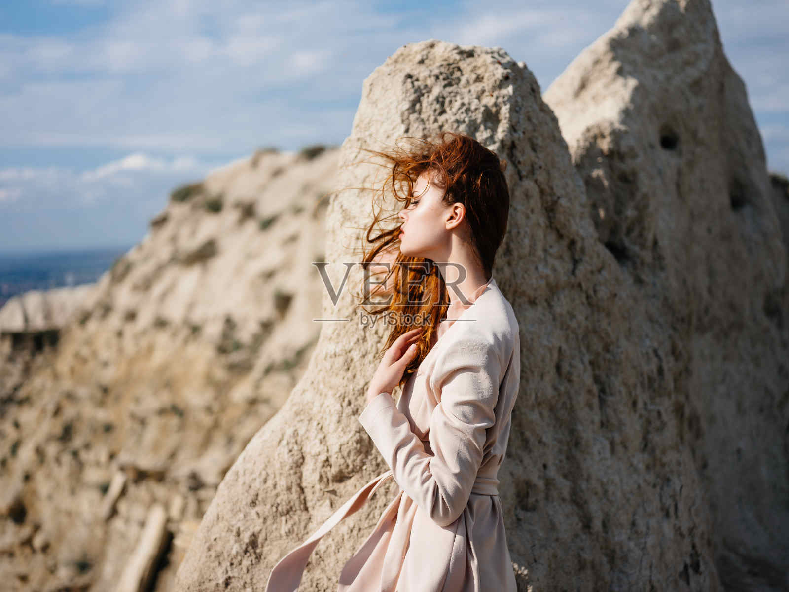 漂亮的女人在沙滩上的岩石旁摆姿势，看起来很吸引人照片摄影图片