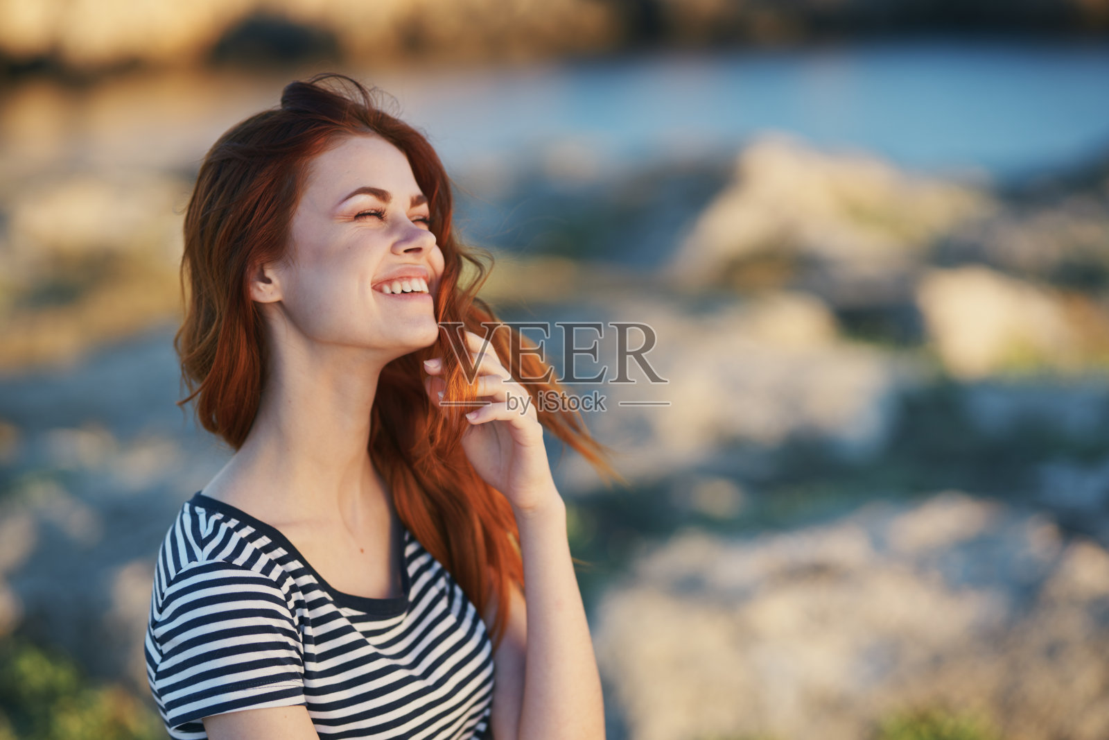 浪漫的女人在户外的山间穿一件条纹t恤，呼吸着清新的海风照片摄影图片