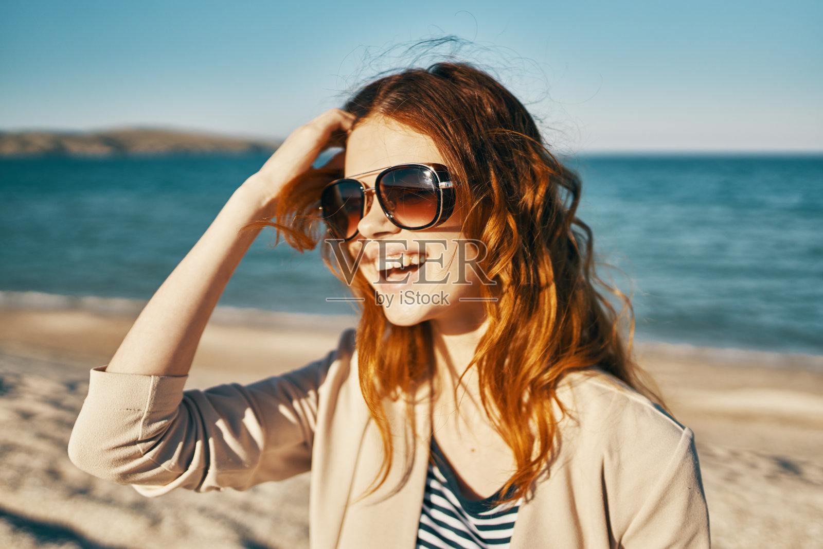 戴着墨镜的美女在山上海边的沙滩上照片摄影图片