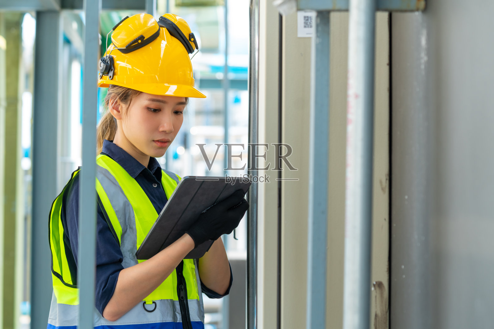 在室外建筑工地屋顶工作的女工程师。照片摄影图片
