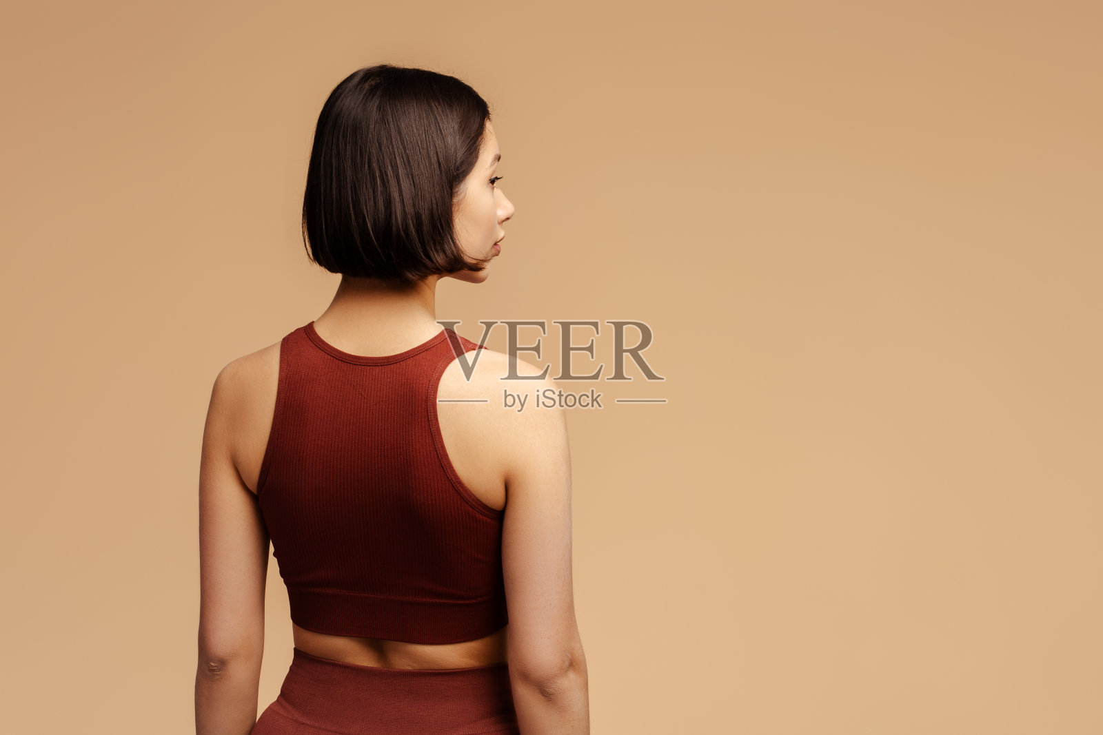 那个穿着运动服的年轻女子的后视图，站在孤立的地方照片摄影图片