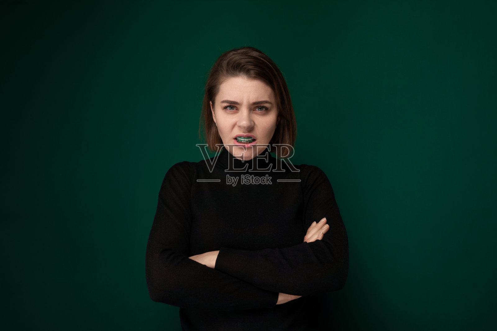 绿色背景下双臂交叉的女人照片摄影图片