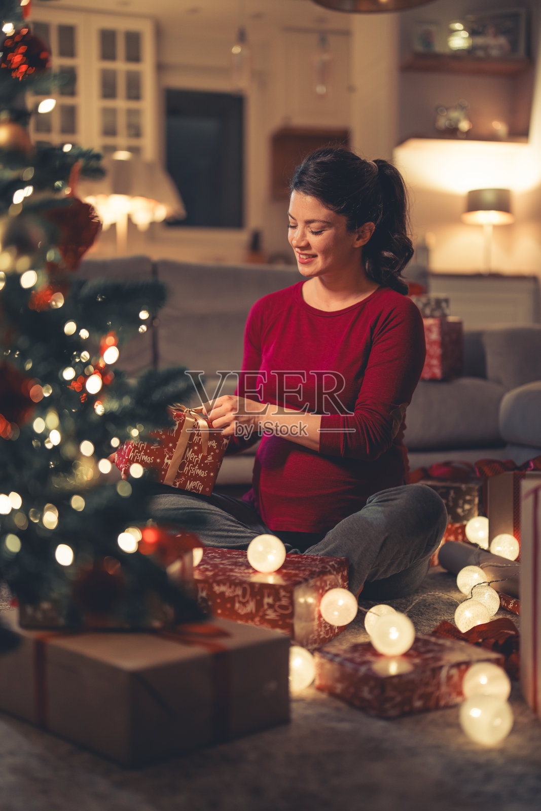 一个美丽快乐的年轻成年女子坐在客厅的地上准备圣诞礼物照片摄影图片