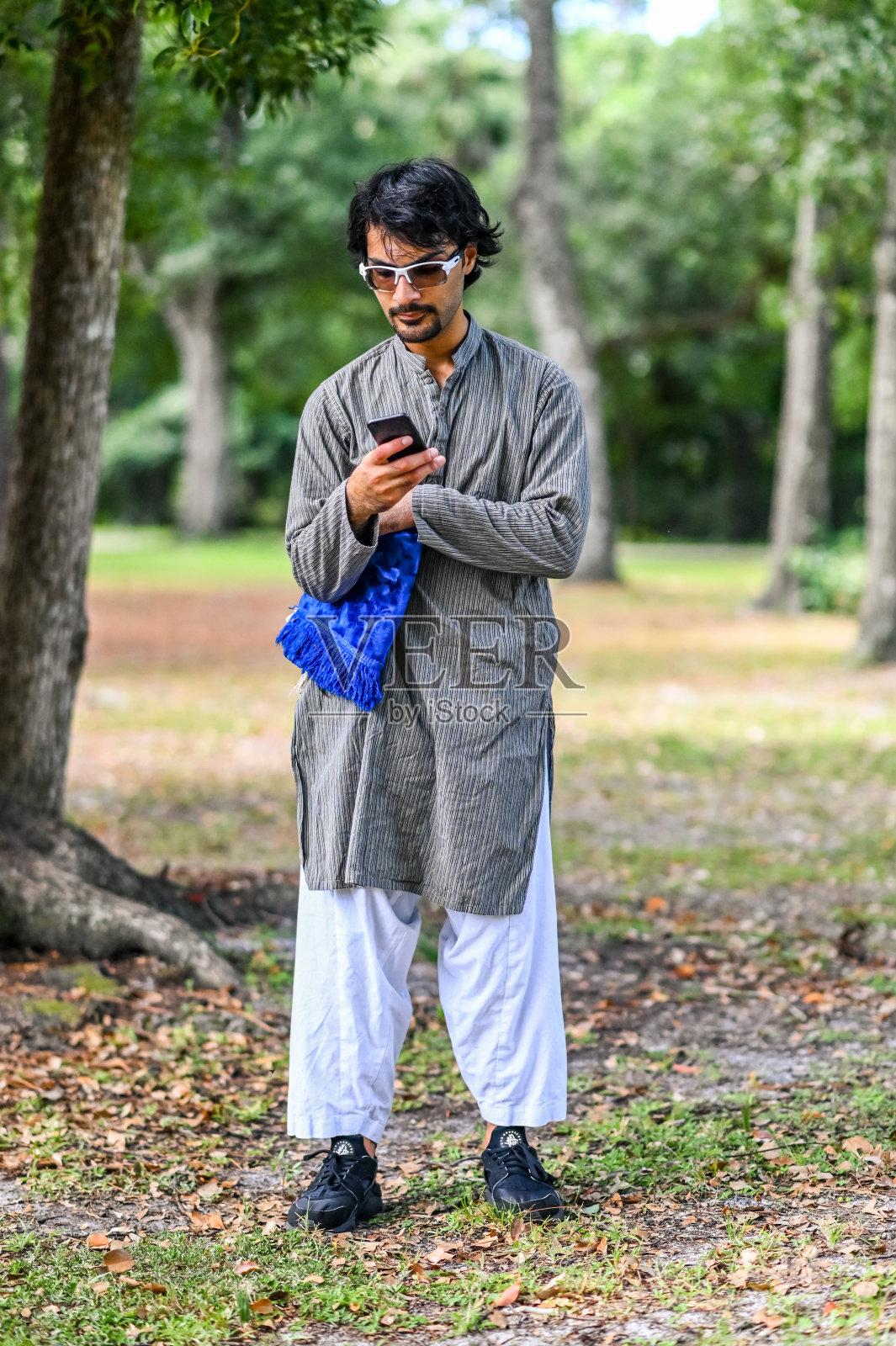 年轻的中东穆斯林男子使用手机App查找朝拜方向照片摄影图片