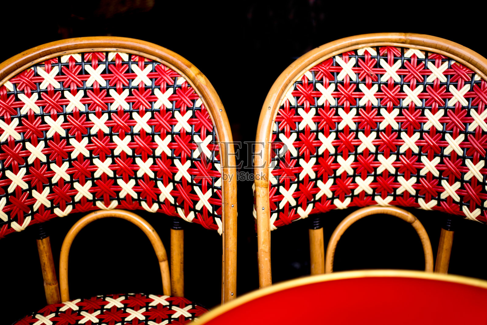 巴黎，法国:两个复古的红色柳条椅子，桌子，黑色背景照片摄影图片
