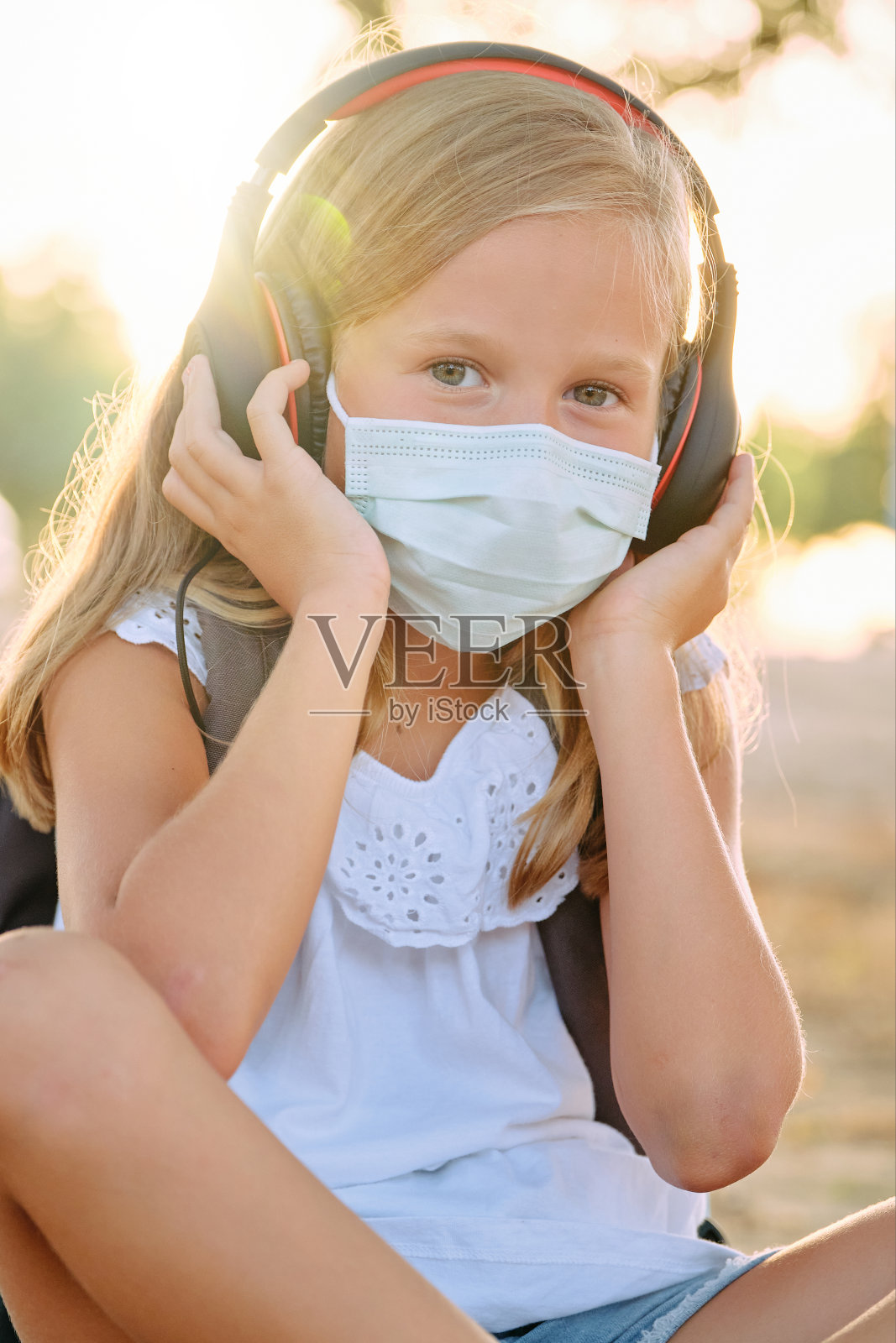 戴着防护口罩和耳机的可爱女孩照片摄影图片