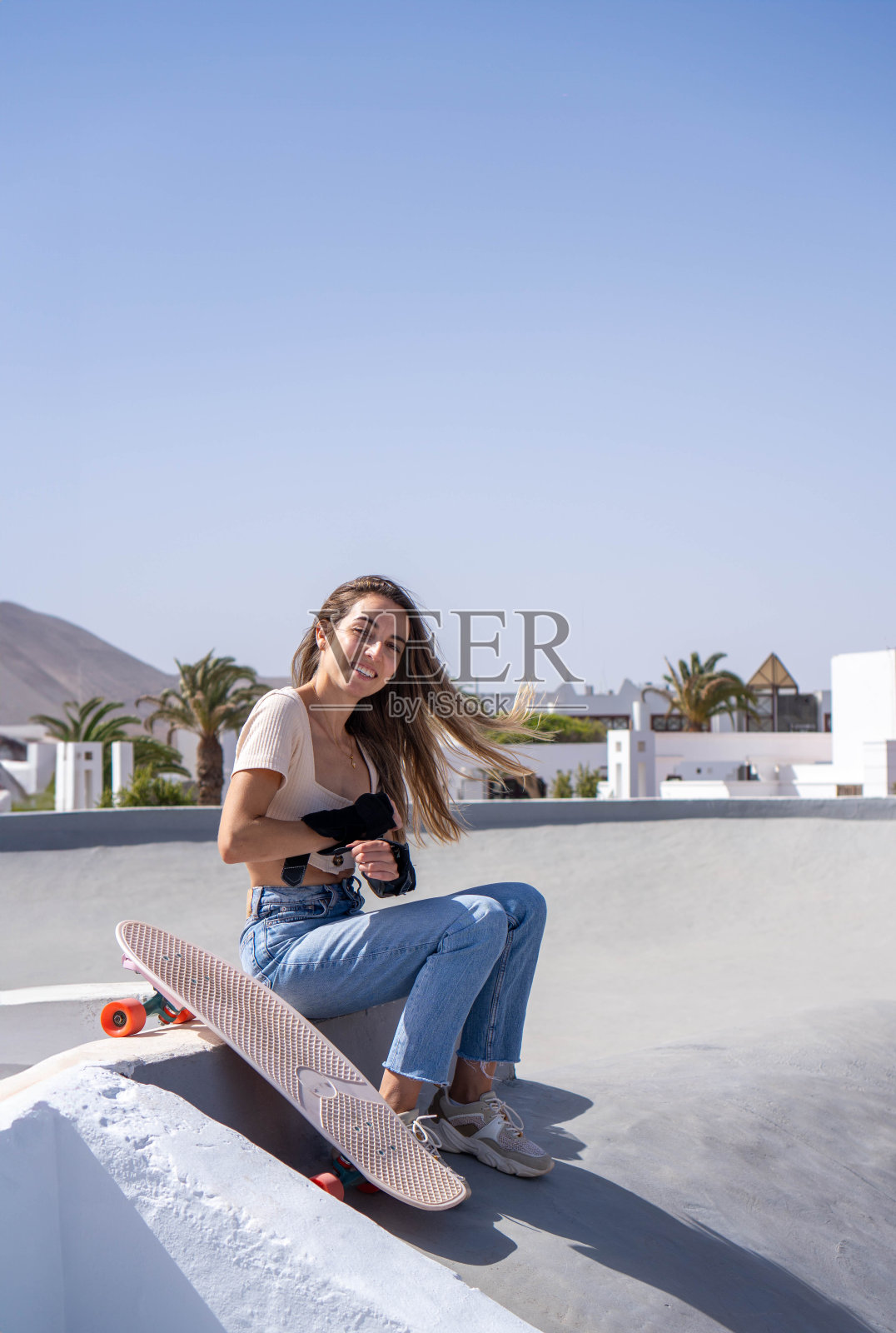 年轻女子坐在窗台上玩滑板照片摄影图片