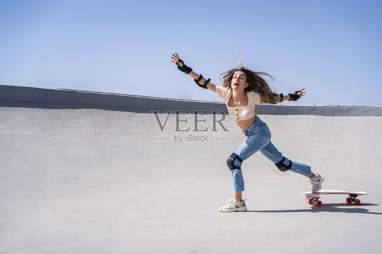 阳光明媚的一天，一名女子在滑板公园从滑板上摔了下来照片摄影图片