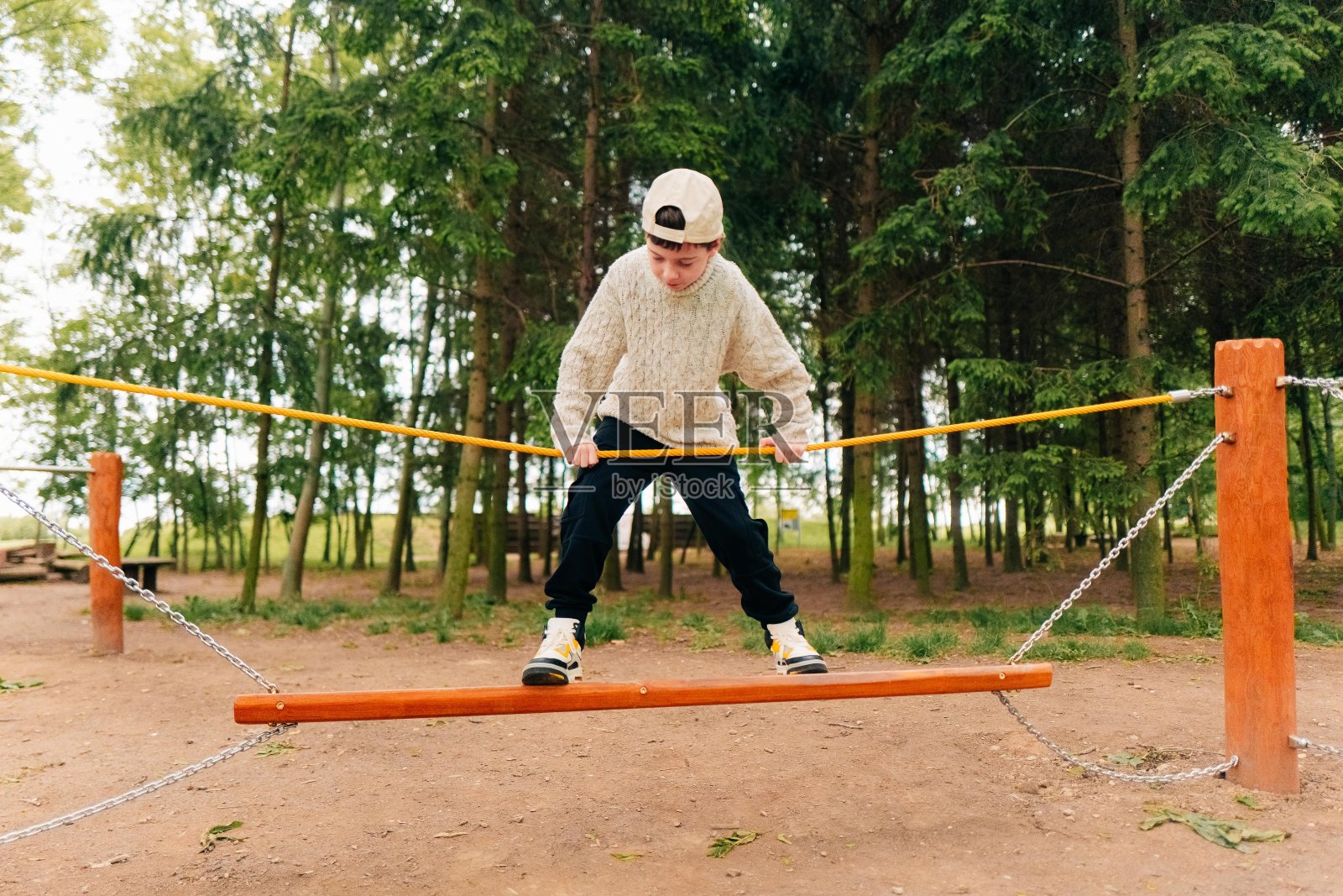 一个十几岁的男孩在操场上克服了绳镇的障碍照片摄影图片
