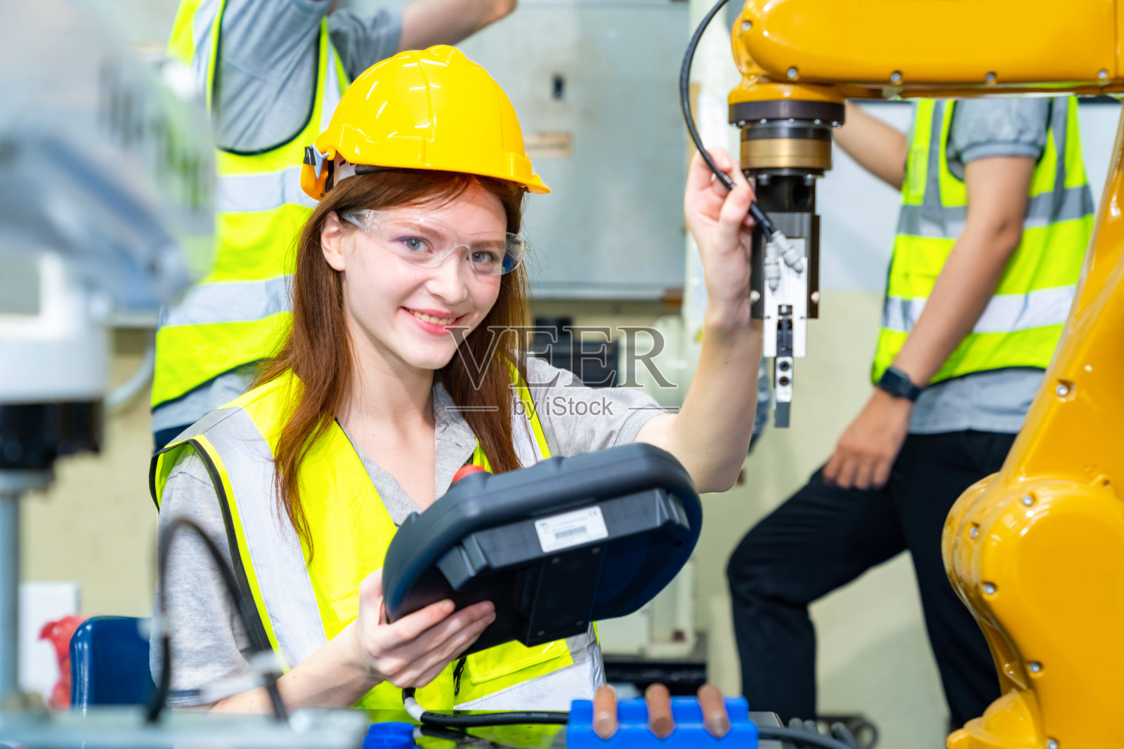 在工厂里操作机器人的女工程师。照片摄影图片