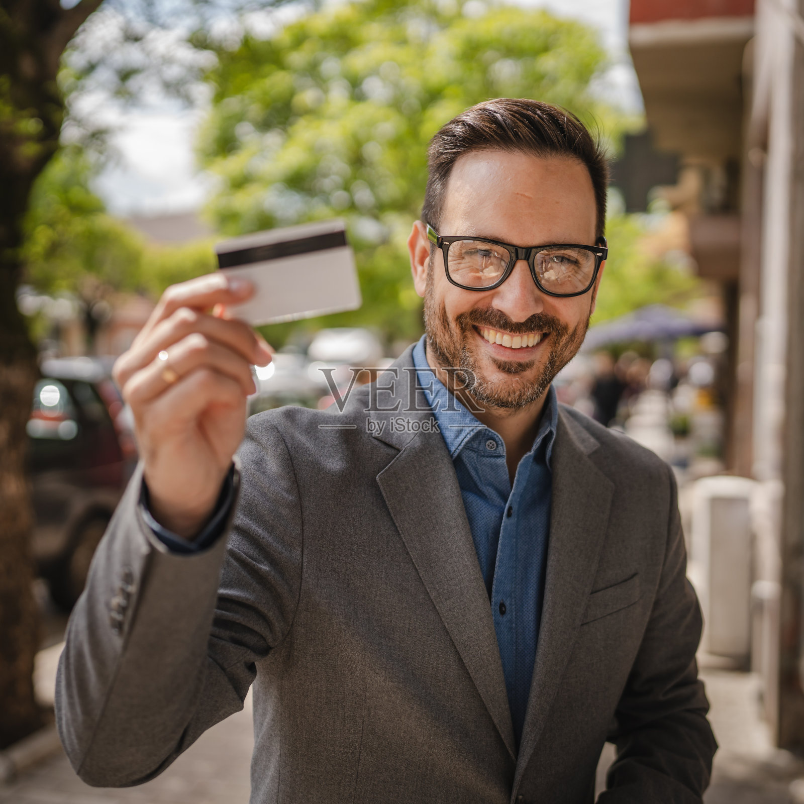成年白人男子手持信用卡站在街上的肖像照片摄影图片