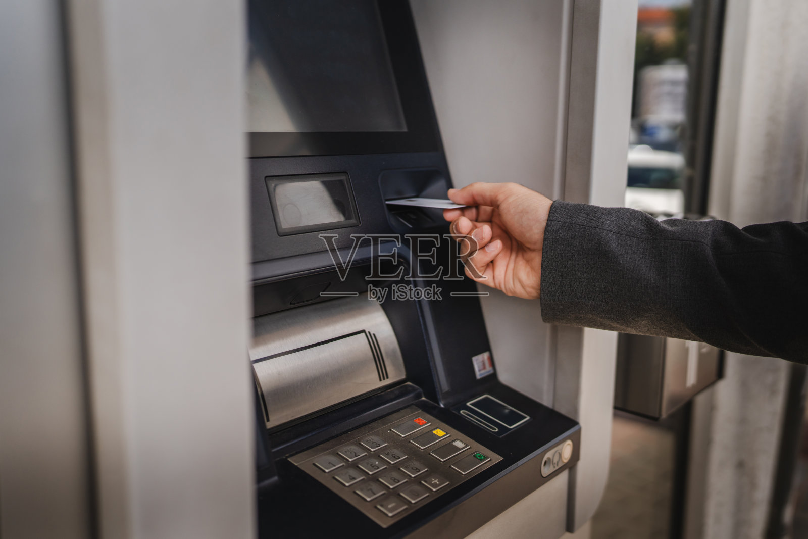 男子手持信用卡在街上使用自动取款机的特写照片摄影图片