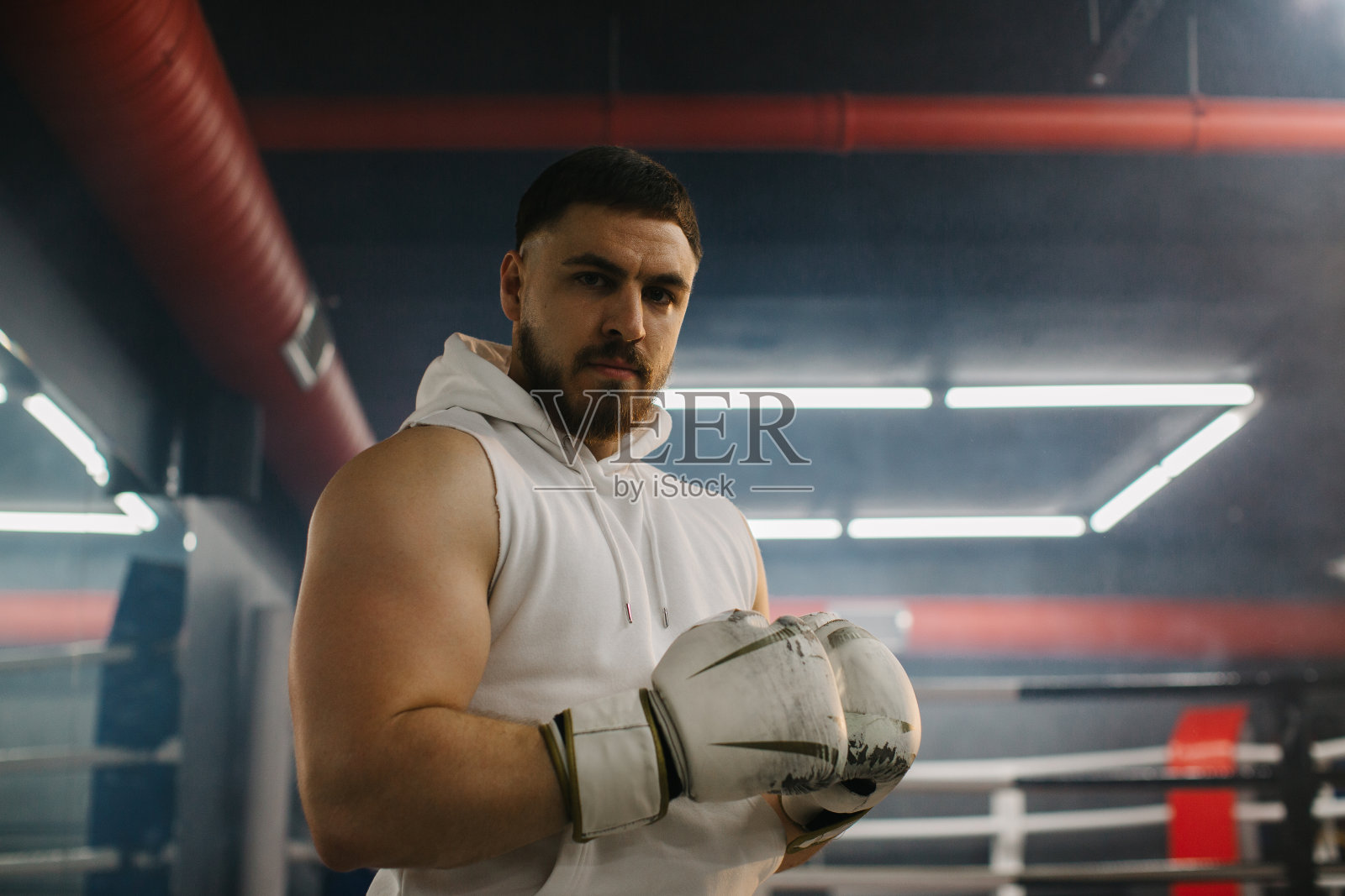 拳击俱乐部拳台背景上戴着手套的男拳击手。照片摄影图片